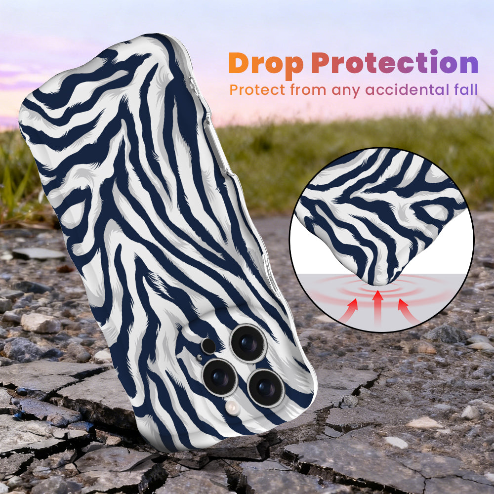 Navy and white zebra print Wavy Luxe MagSafe iPhone case standing on cracked rock at sunset, with an inset showing the cushioned wavy edge that absorbs accidental drops.