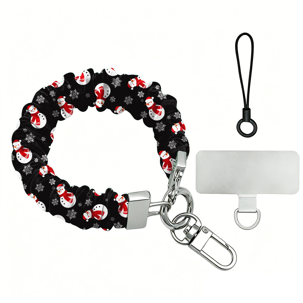 Snowman scrunchie phone wrist strap laid flat with silver clasp and phone tab, black print with white snowmen in red scarves and Santa hats