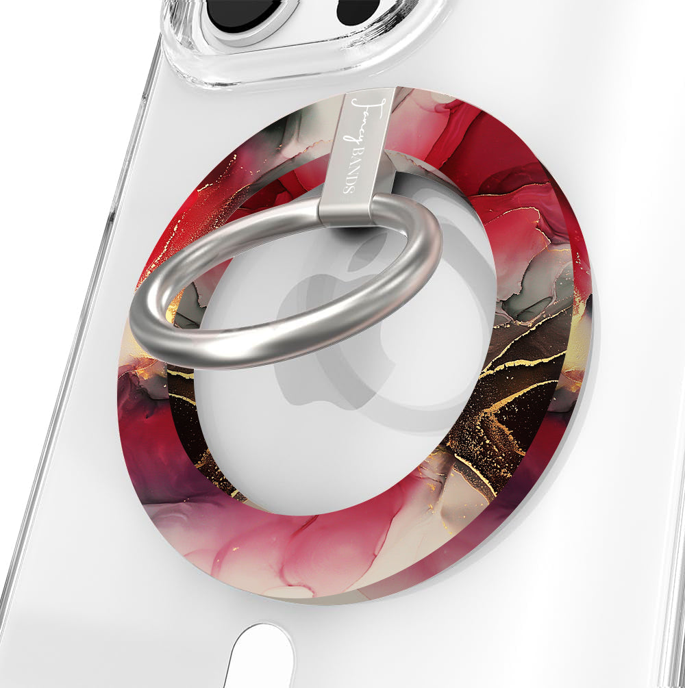 Velvet Vixen Hold It Fancy MagSafe grip ring on a clear iPhone case, crimson and black alcohol-ink marble with gold veining around the silver rotating ring.