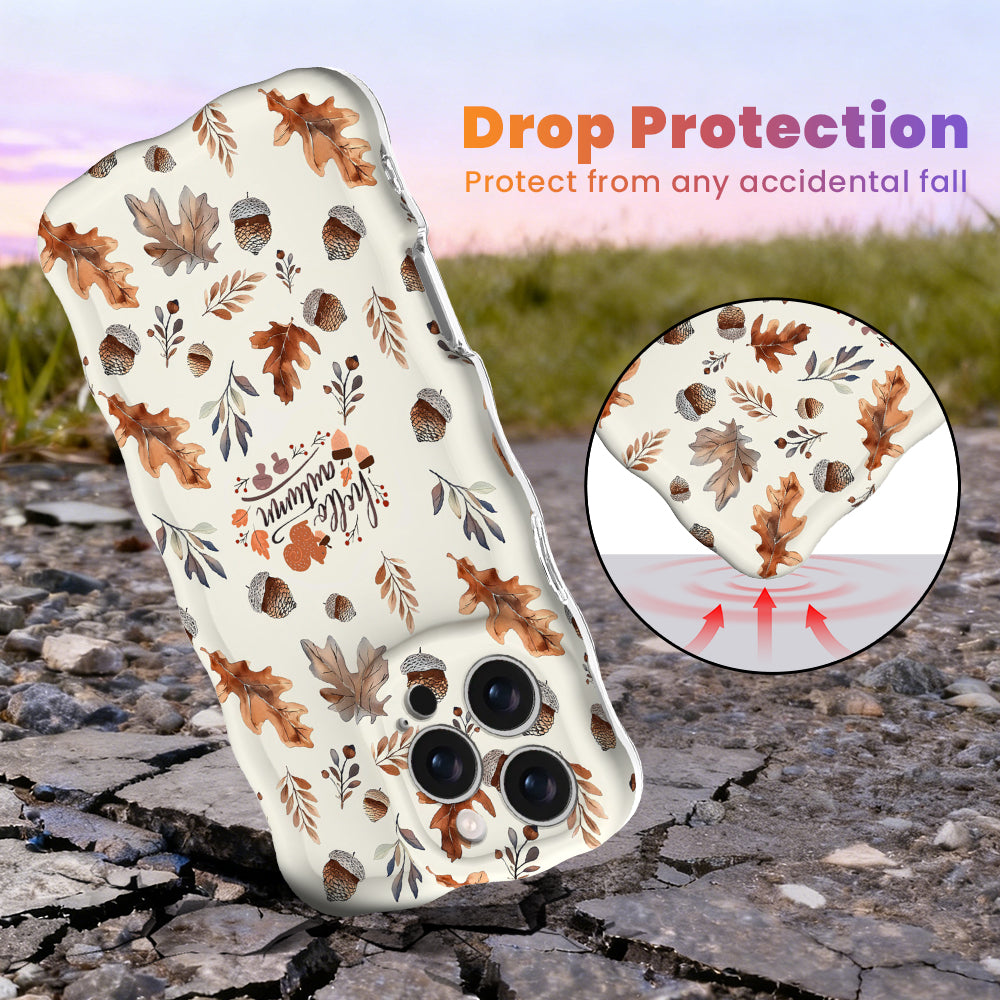 Drop protection diagram for the Nutty For Fall Wavy Luxe iPhone case, showing the shock-absorbing raised edges that protect the cream acorn and oak leaf print against accidental falls.