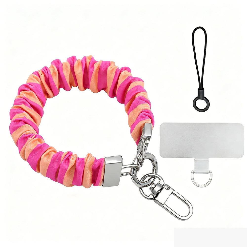 Pink and orange striped Candy Citrus Stripes scrunchie phone wrist strap clipped to the matching hot pink and citrus orange striped Wavy Luxe iPhone case, styled on a playful pink and orange heart print background.