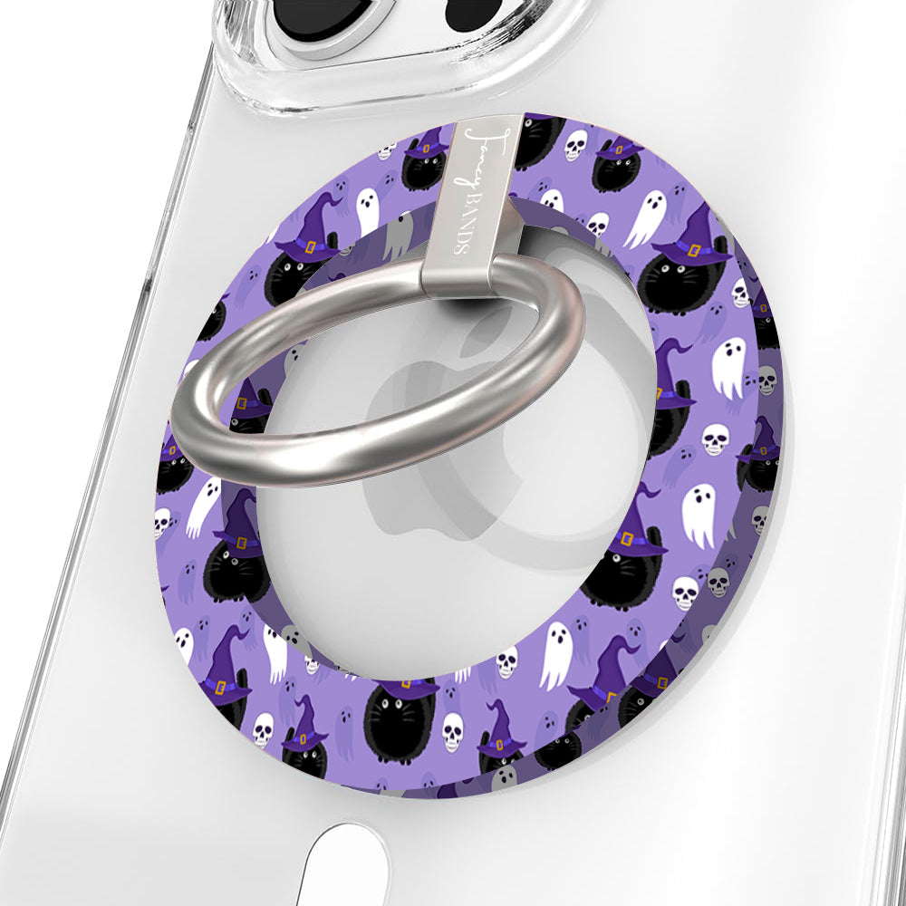 Ghostly Whisker's Hold It Fancy MagSafe grip ring close-up on a clear iPhone case, showing the lavender ring with white ghosts, black cats and witch hats around the silver rotating ring.