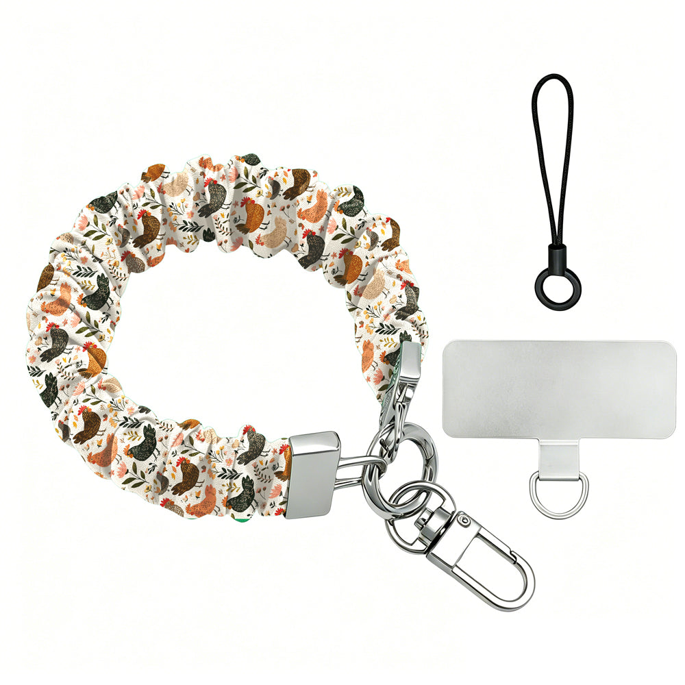 Cream and floral Cluckin' Cute scrunchie phone wrist strap with a hand-illustrated chicken and wildflower print, clipped to the matching farmhouse chicken Wavy Luxe iPhone case, styled on a rustic wood and burlap background.
