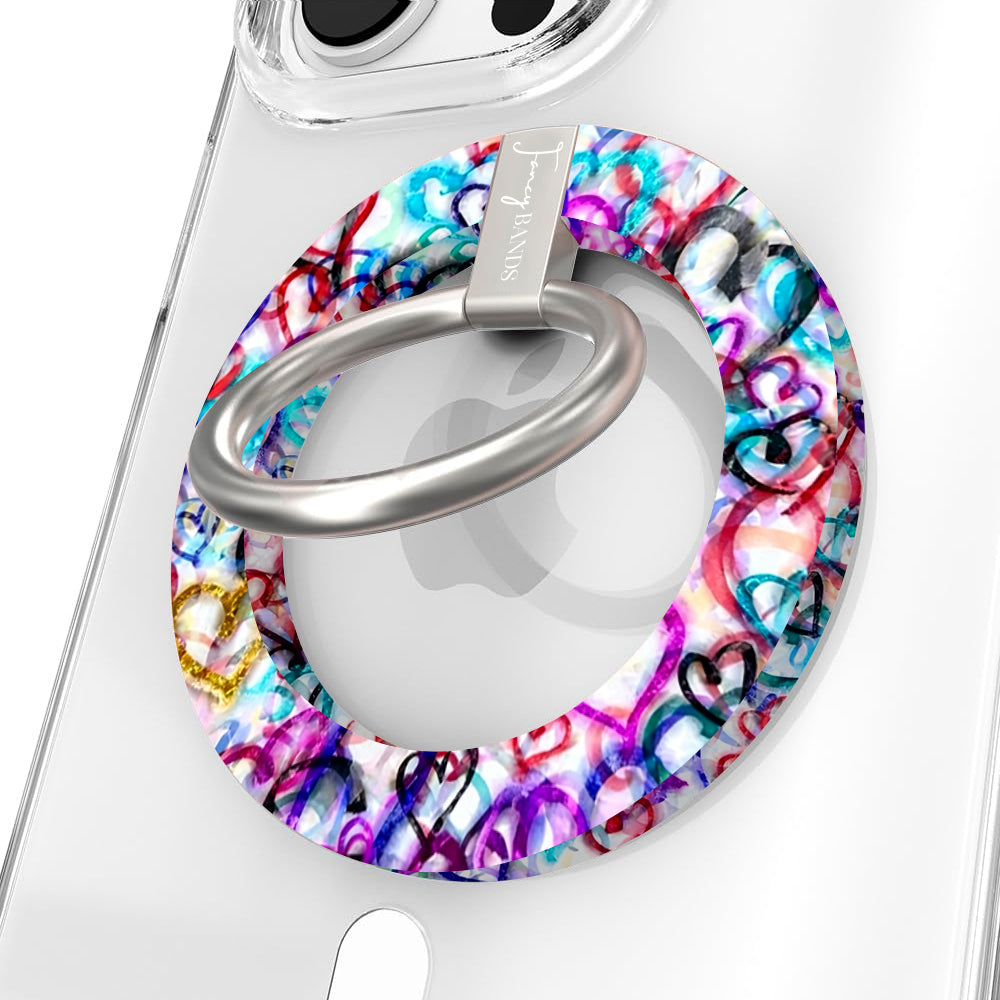 Love Out Loud colorful graffiti heart pattern MagSafe phone grip ring with overlapping neon pink purple and turquoise hearts compatible with iPhone and Samsung