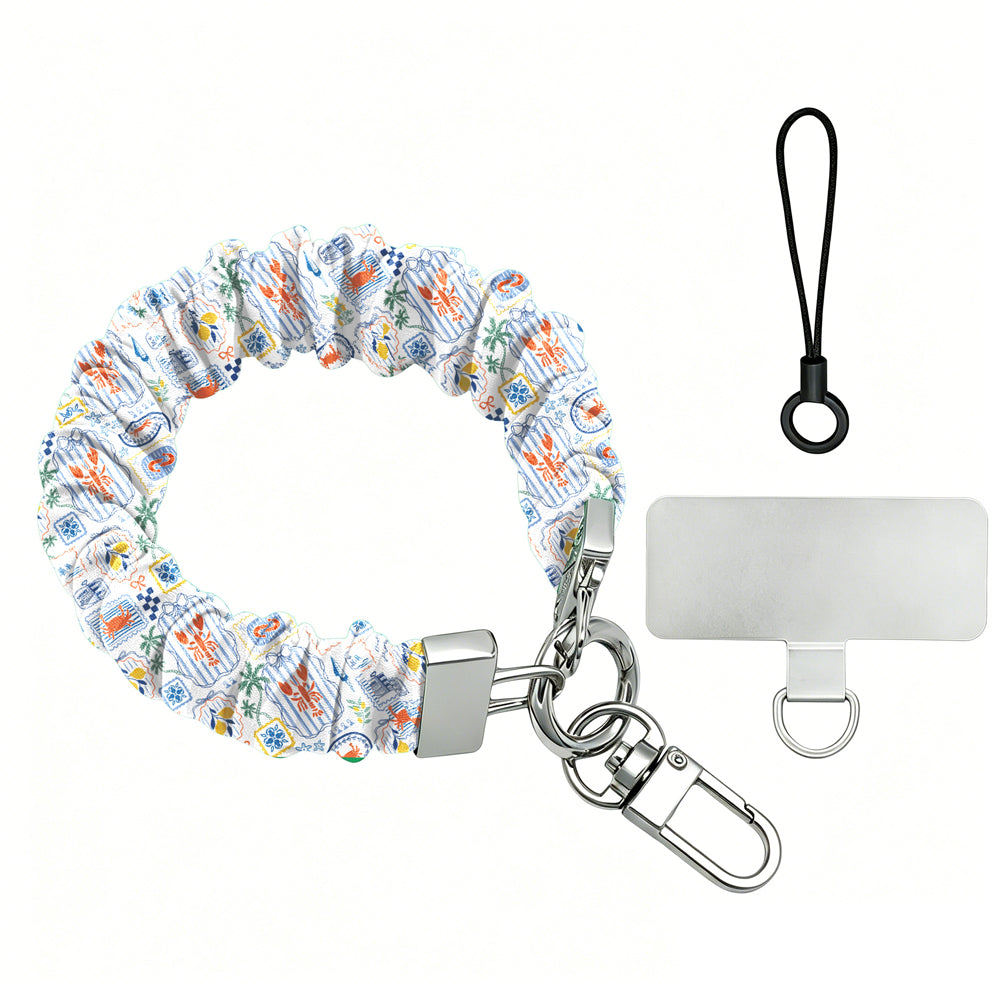 Blue and yellow La Dolce Summer scrunchie phone wrist strap in gingham and lemon print, clipped to the matching Amalfi Coast Wavy Luxe iPhone case with Italia and Capri travel stamps, styled on a blue-and-yellow Mediterranean palm and seashell print background.