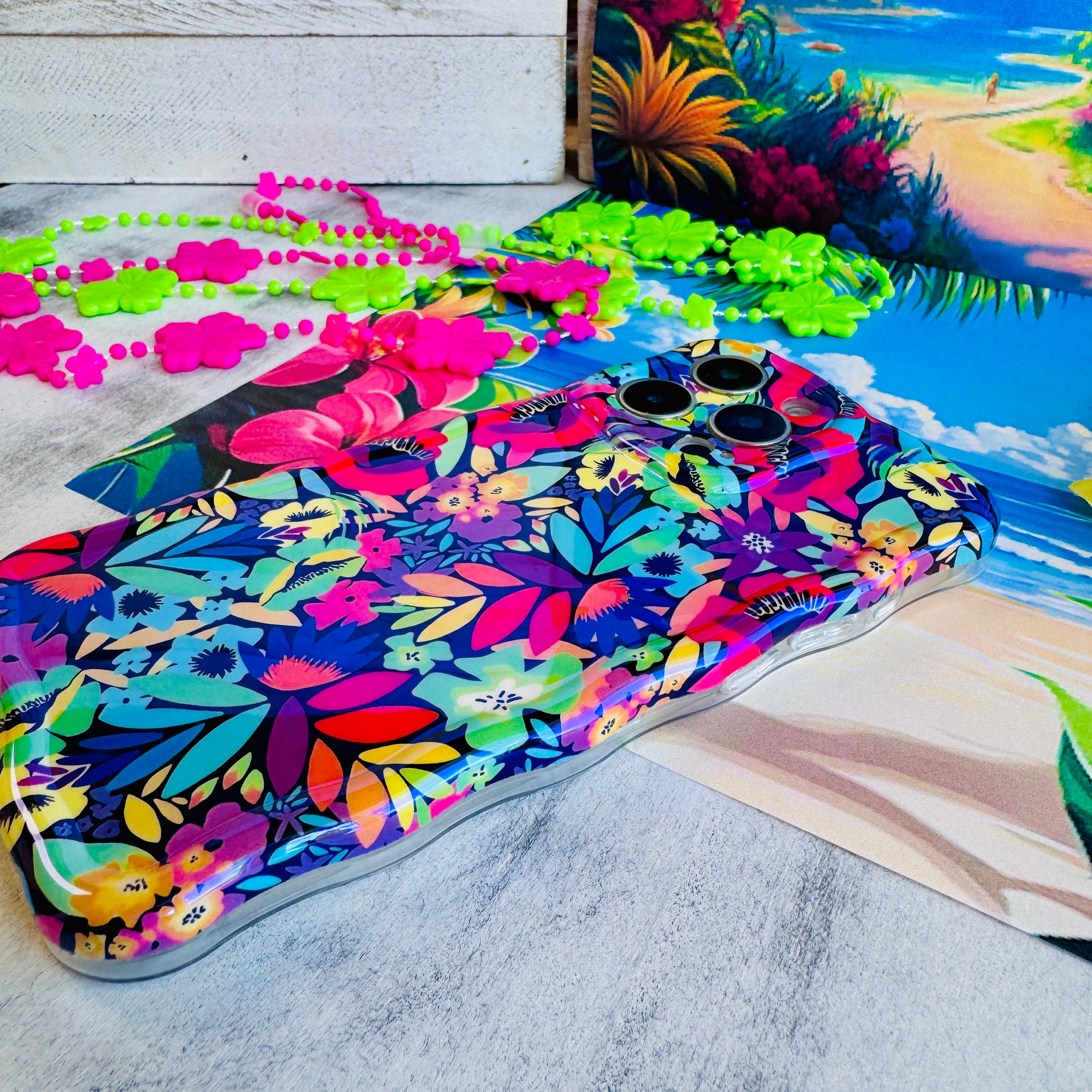 Colorful floral-patterned towel with sunglasses and beads on a beach-themed background