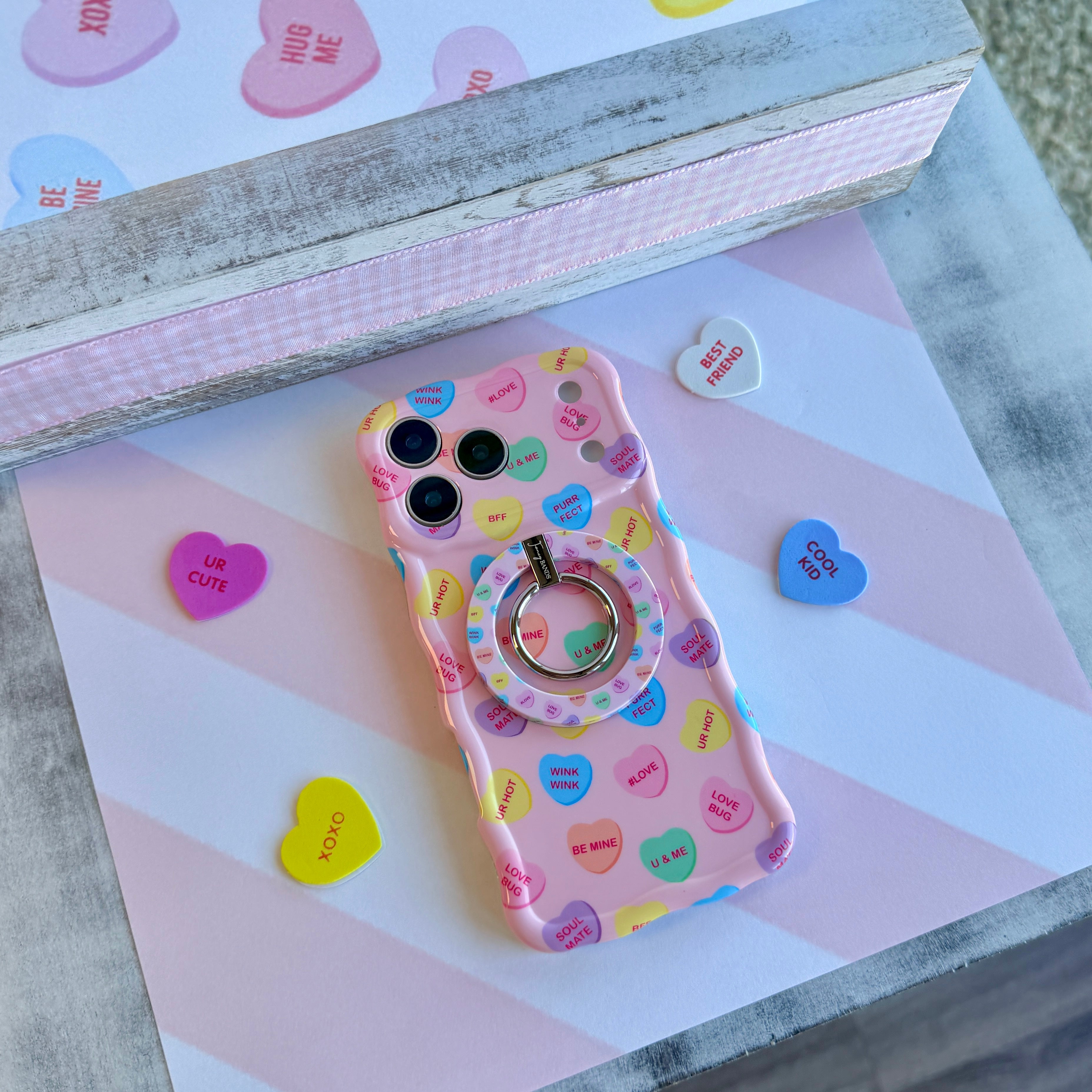 Conversation Hearts pattern MagSafe phone grip ring with pastel candy hearts and "Be Mine" text on pink background compatible with iPhone and Samsung