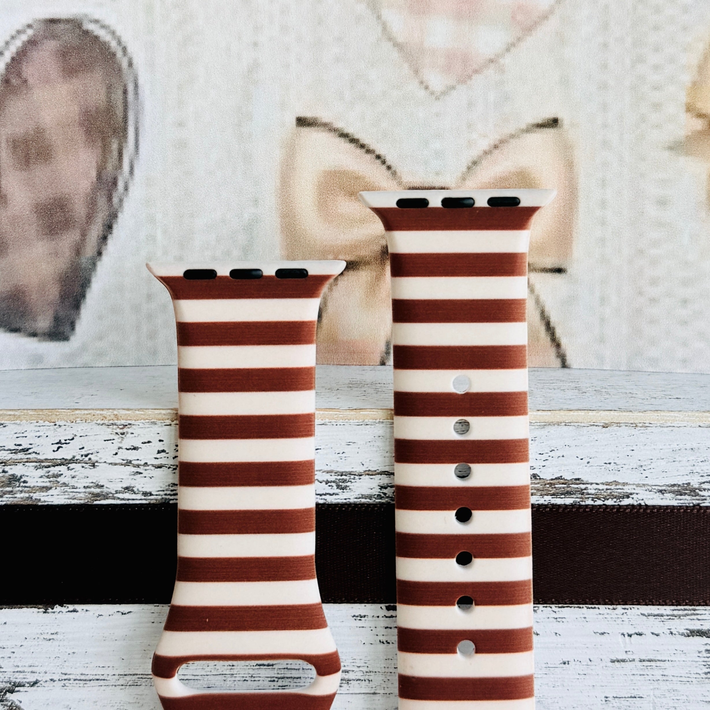 Sweet Espresso Stripes Apple Watch band front view of both strap halves against a cream knit and bow backdrop, showing the brown stripe repeat and adjustment pin holes.