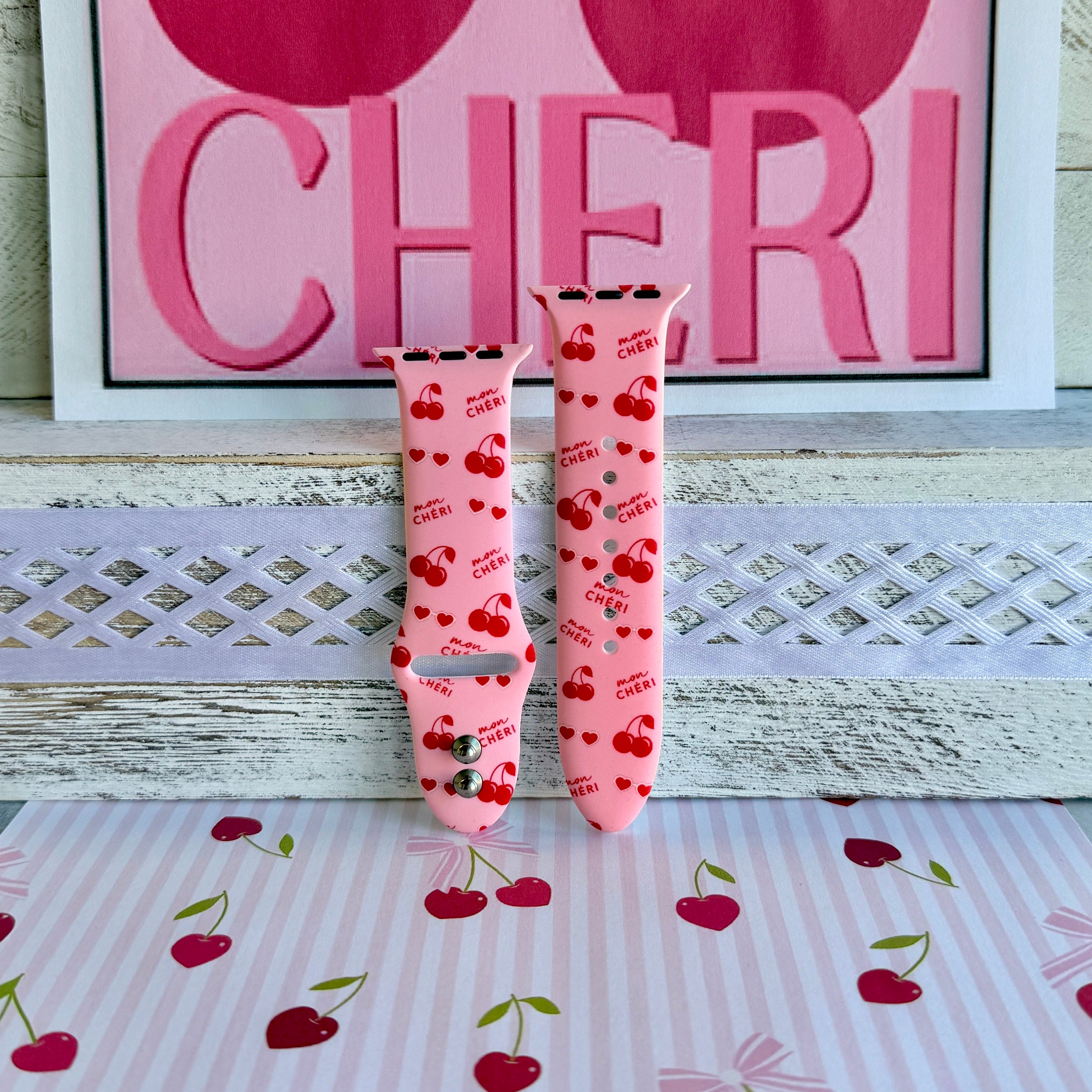 Mon Cheri Apple Watch band with red cherries, hearts, and French text on pink background with CHERI sign