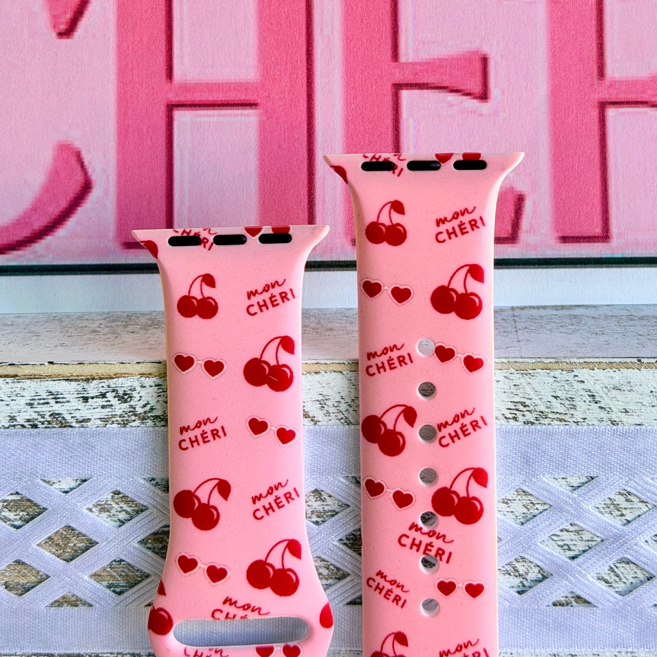 Mon Cheri Apple Watch band with red cherries, hearts, and French text on pink background with CHERI sign