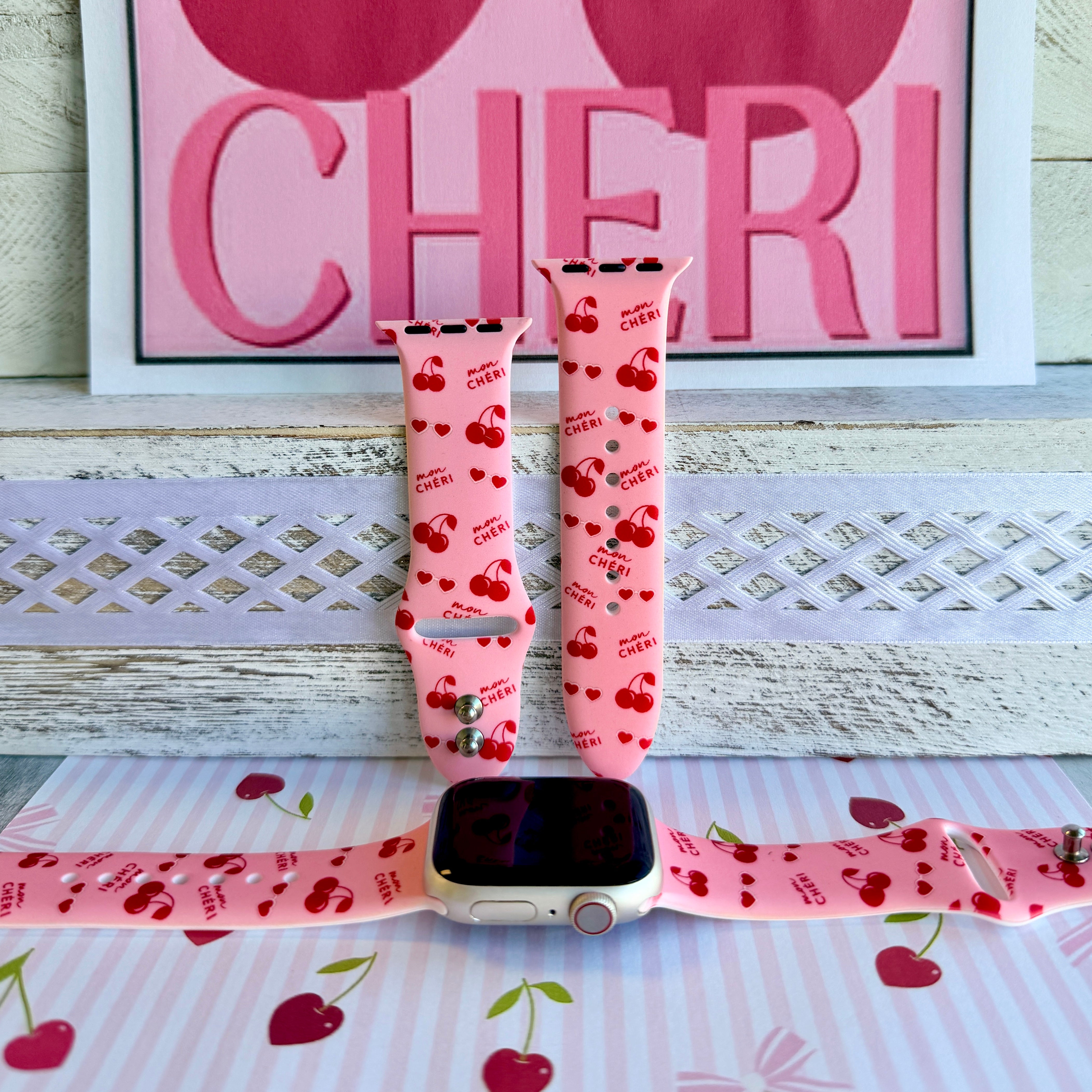 Mon Cheri Apple Watch band with red cherries, hearts, and French text on pink background with CHERI sign