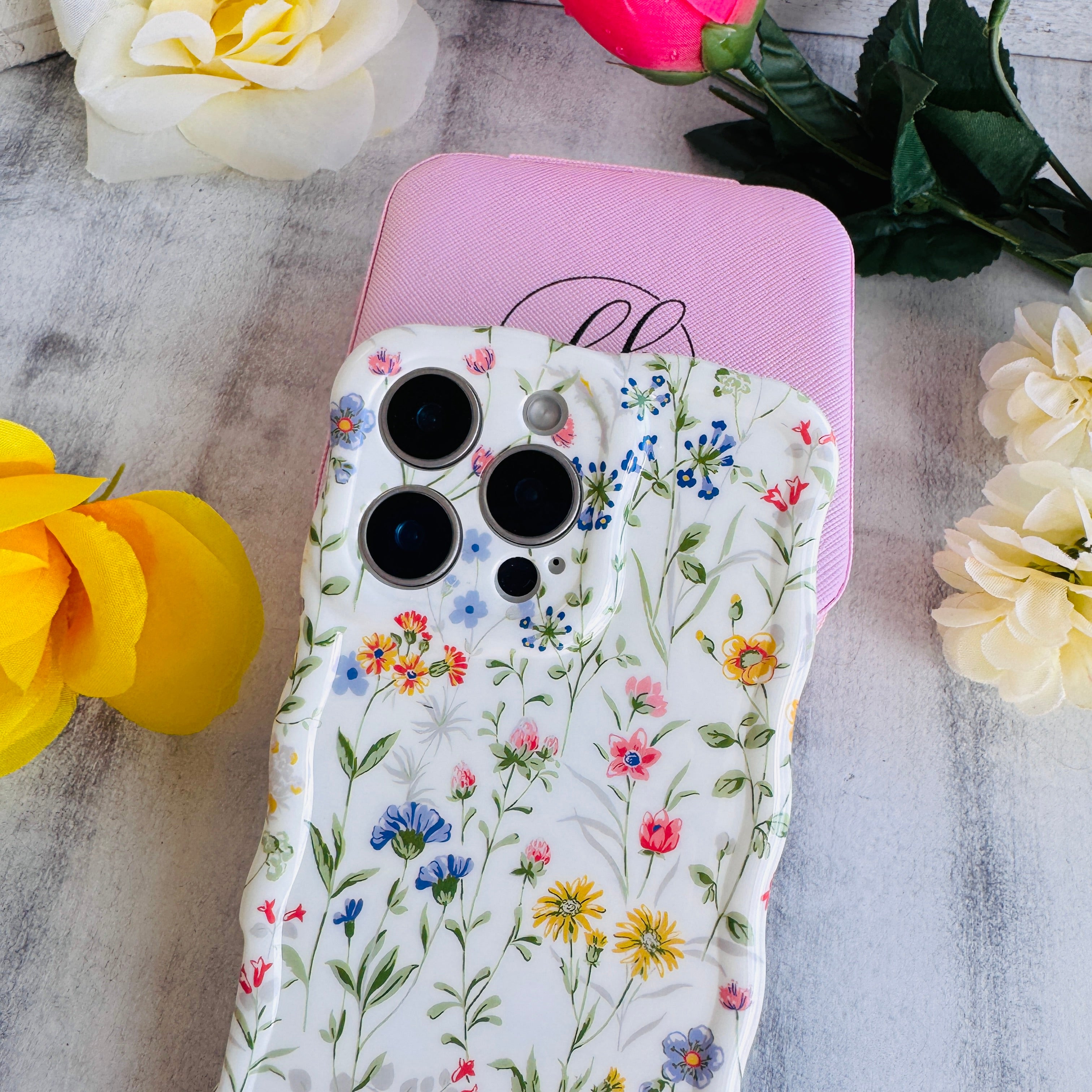 Floral phone case on a pink stand with flowers around