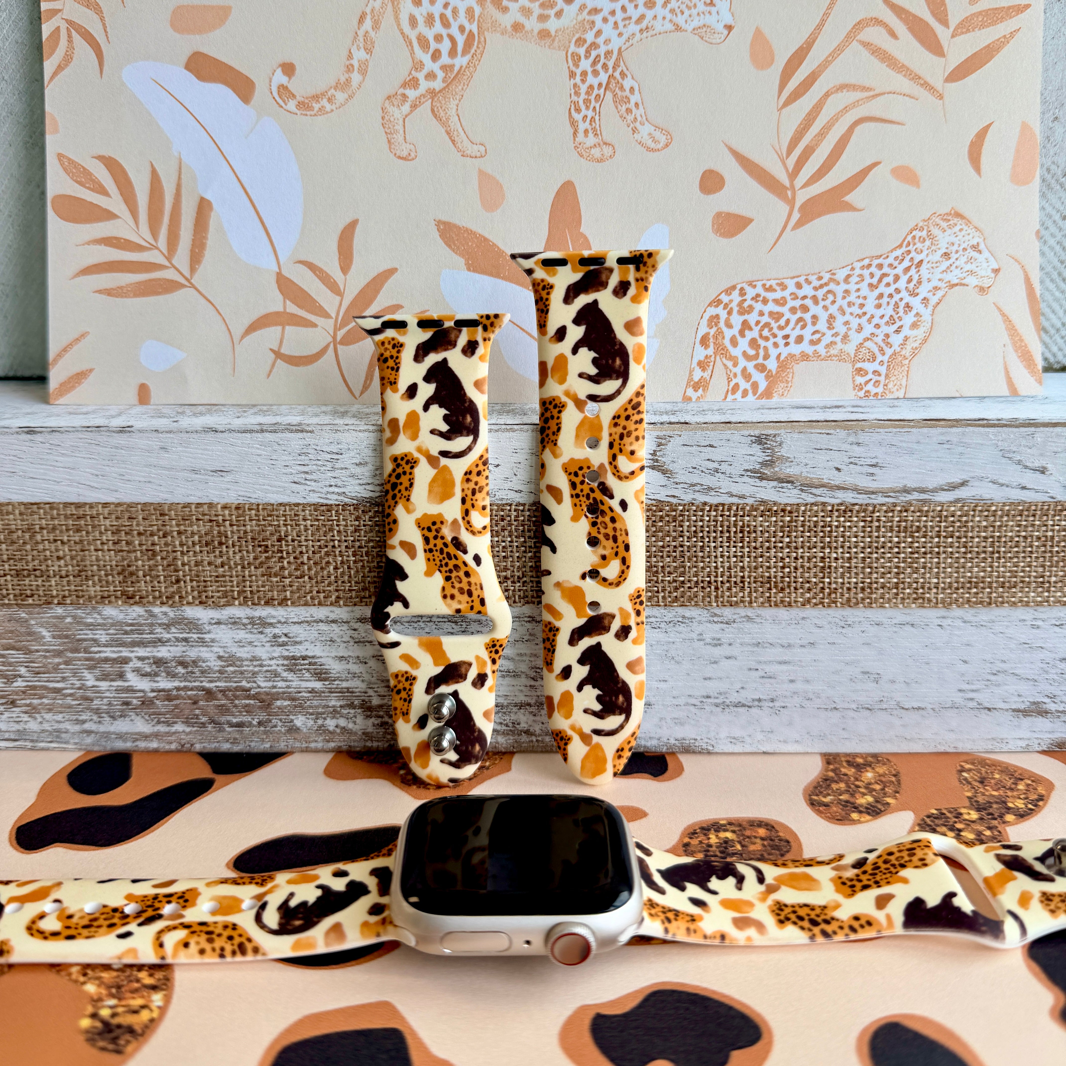 Golden Wildcat Apple Watch band with spotted leopards in golden and brown tones on cream background with safari wallpaper