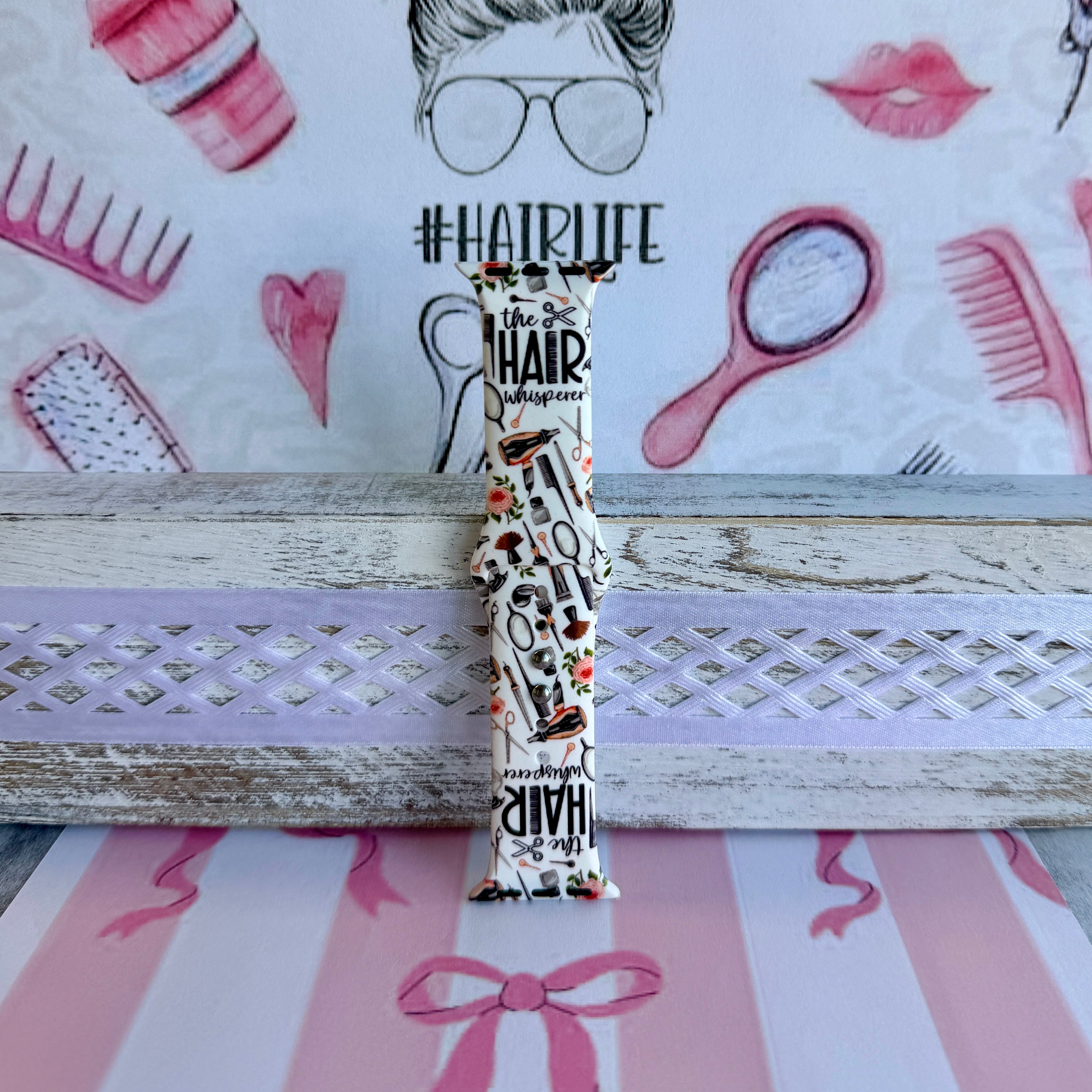 Hair Whisperer Apple Watch band with hairstyling tools, scissors, combs, and roses on white background with #HAIRLIFE backdrop