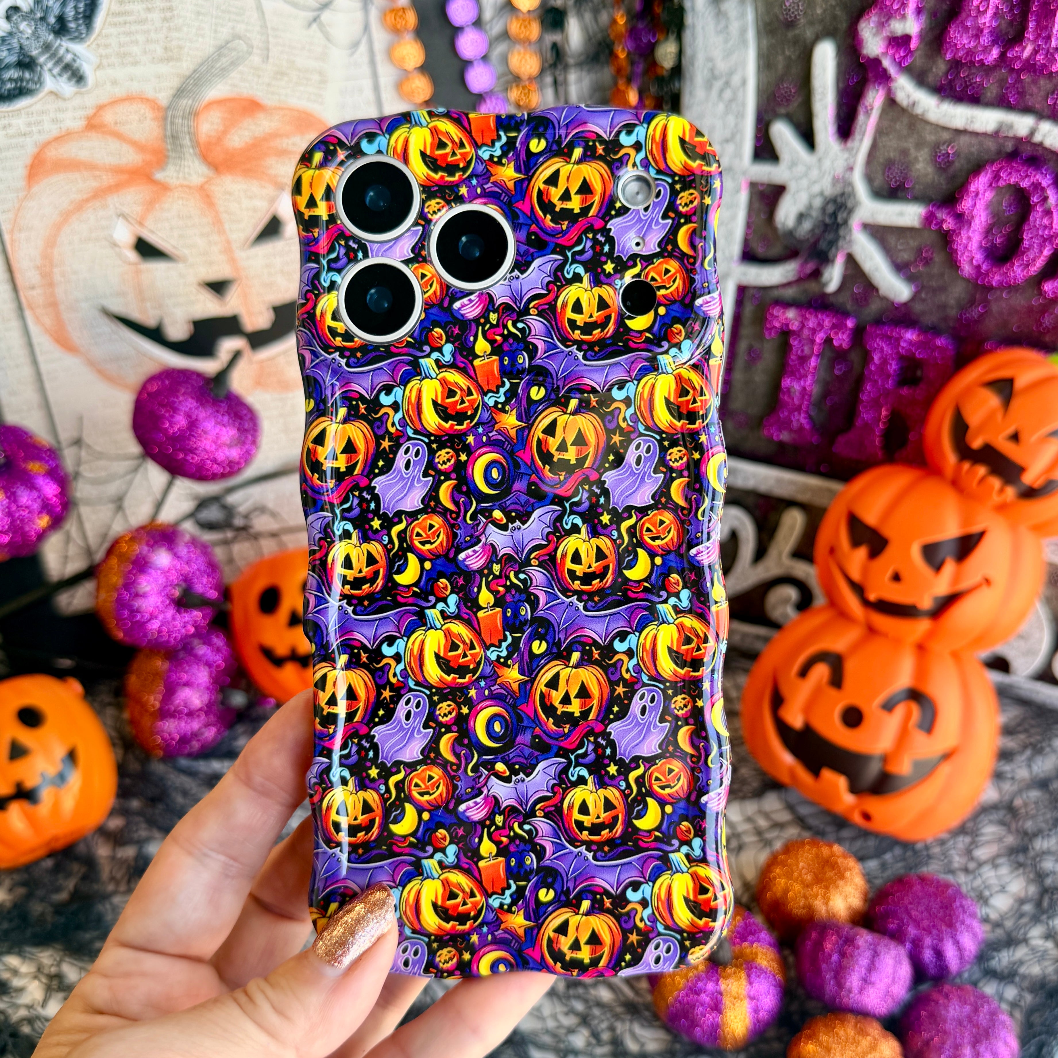 Jack-O-Lantern Jive Wavy Luxe MagSafe iPhone case held in hand, deep violet with glowing orange jack-o-lanterns, lavender ghosts and crescent moons.