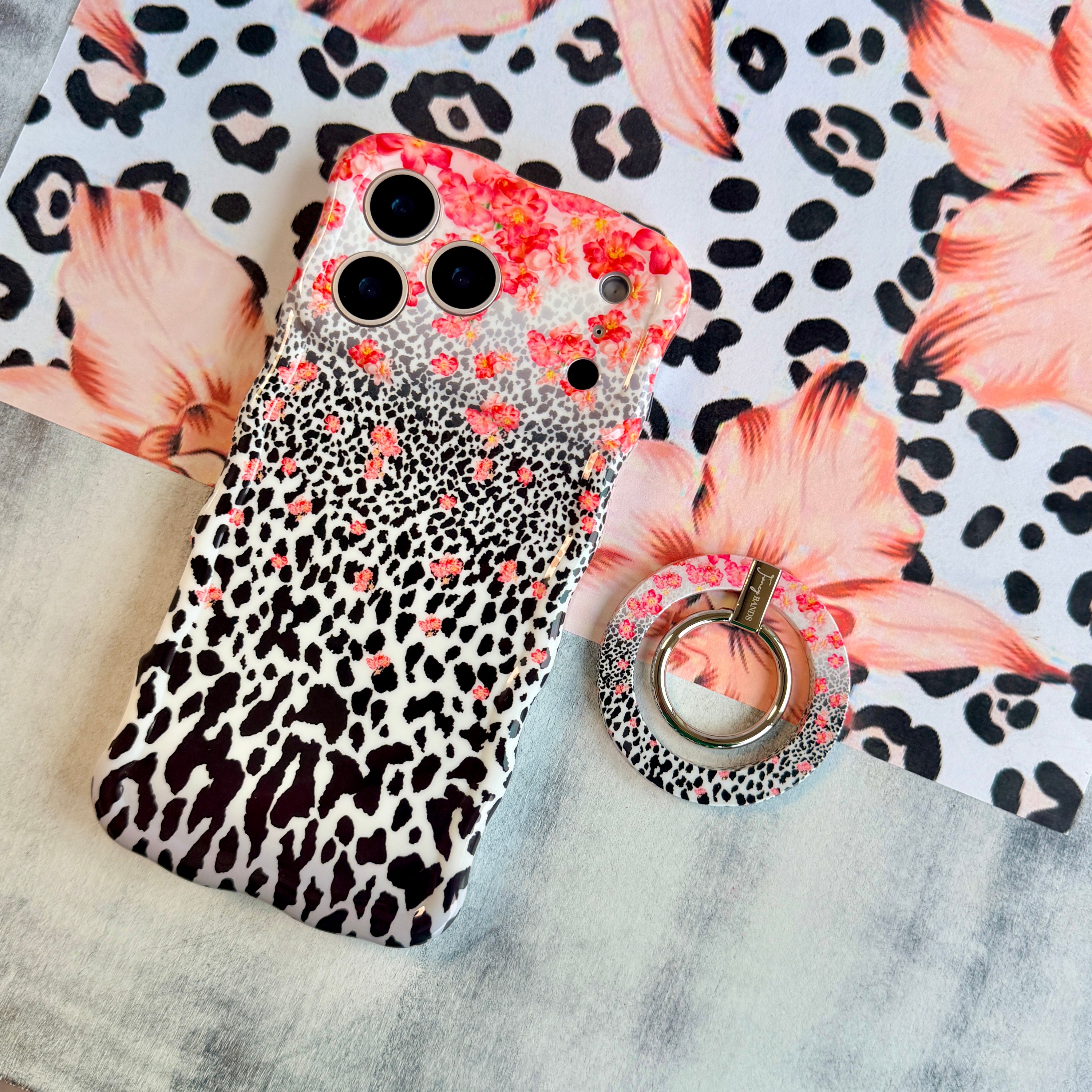 Flower-fetti Leopard pattern MagSafe phone grip ring with pink and orange flowers over black and white leopard spots compatible with iPhone and Samsung