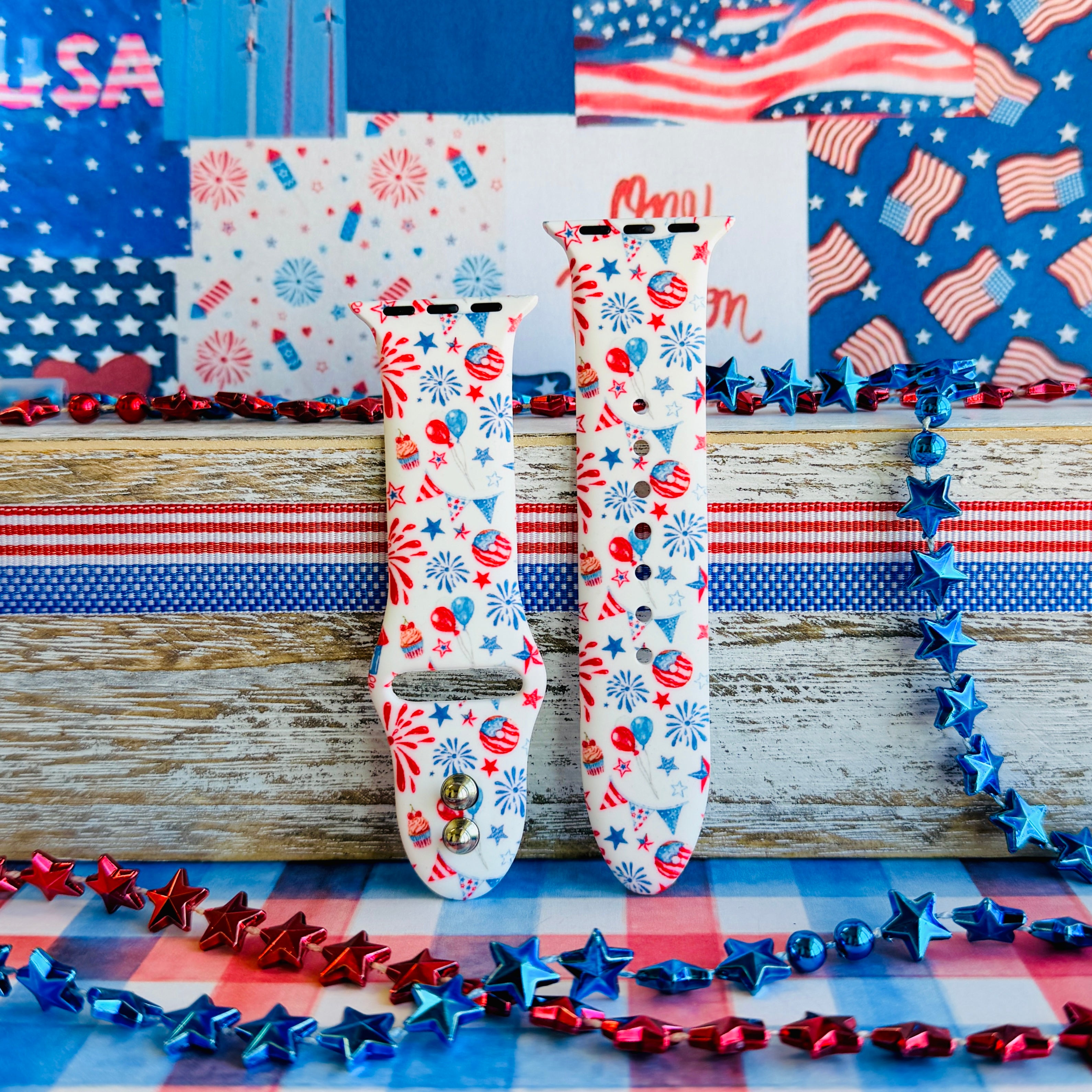 Party In The USA silicone Apple Watch band with fireworks, balloons, cupcakes, flag bunting, and stars in red, white, and blue on a cream base, shown displayed and worn on Apple Watch against a patriotic 4th of July backdrop.