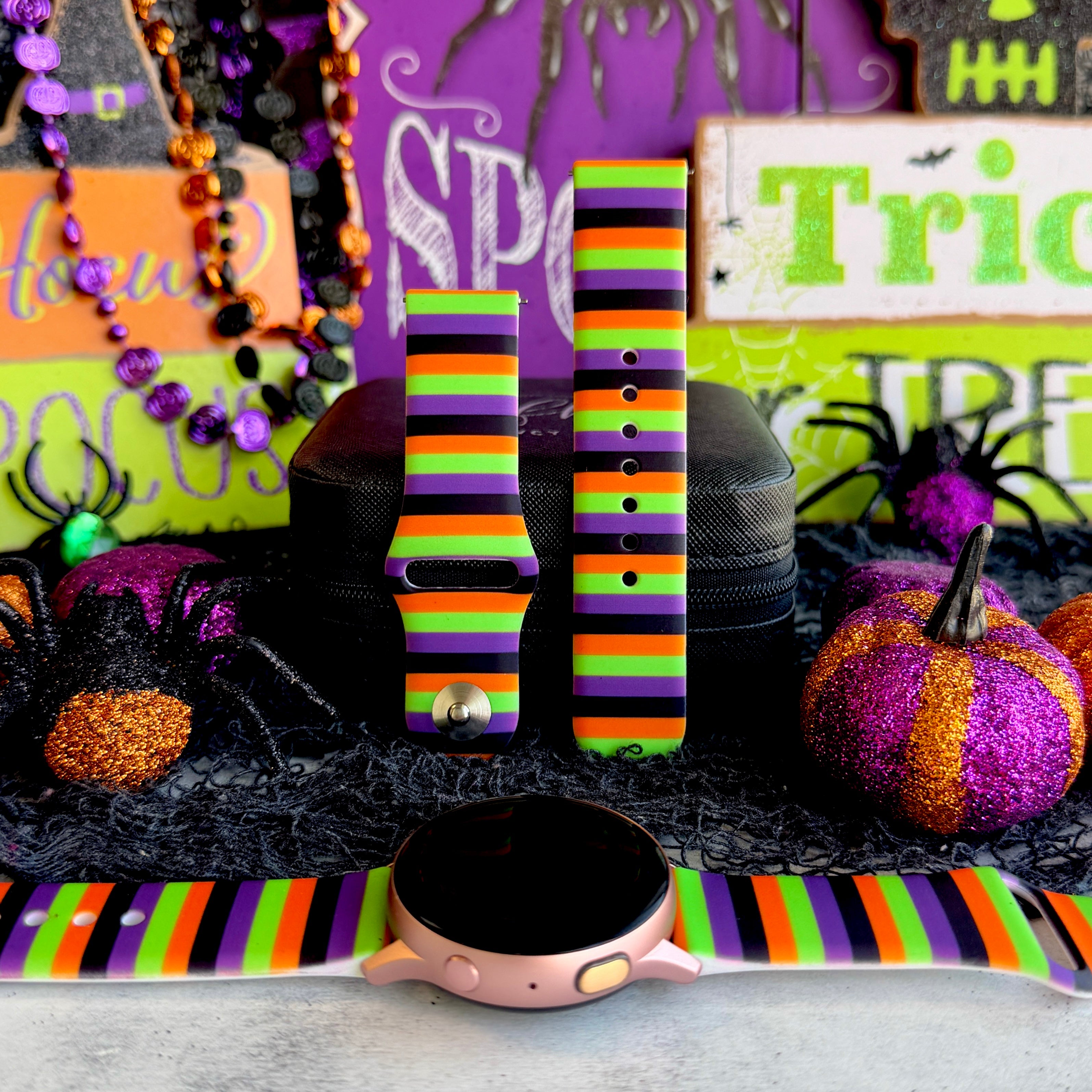 Main Witch Energy silicone Samsung Galaxy Watch band hero shot in black, purple, green and orange stripes, shown with a rose gold Galaxy Watch.