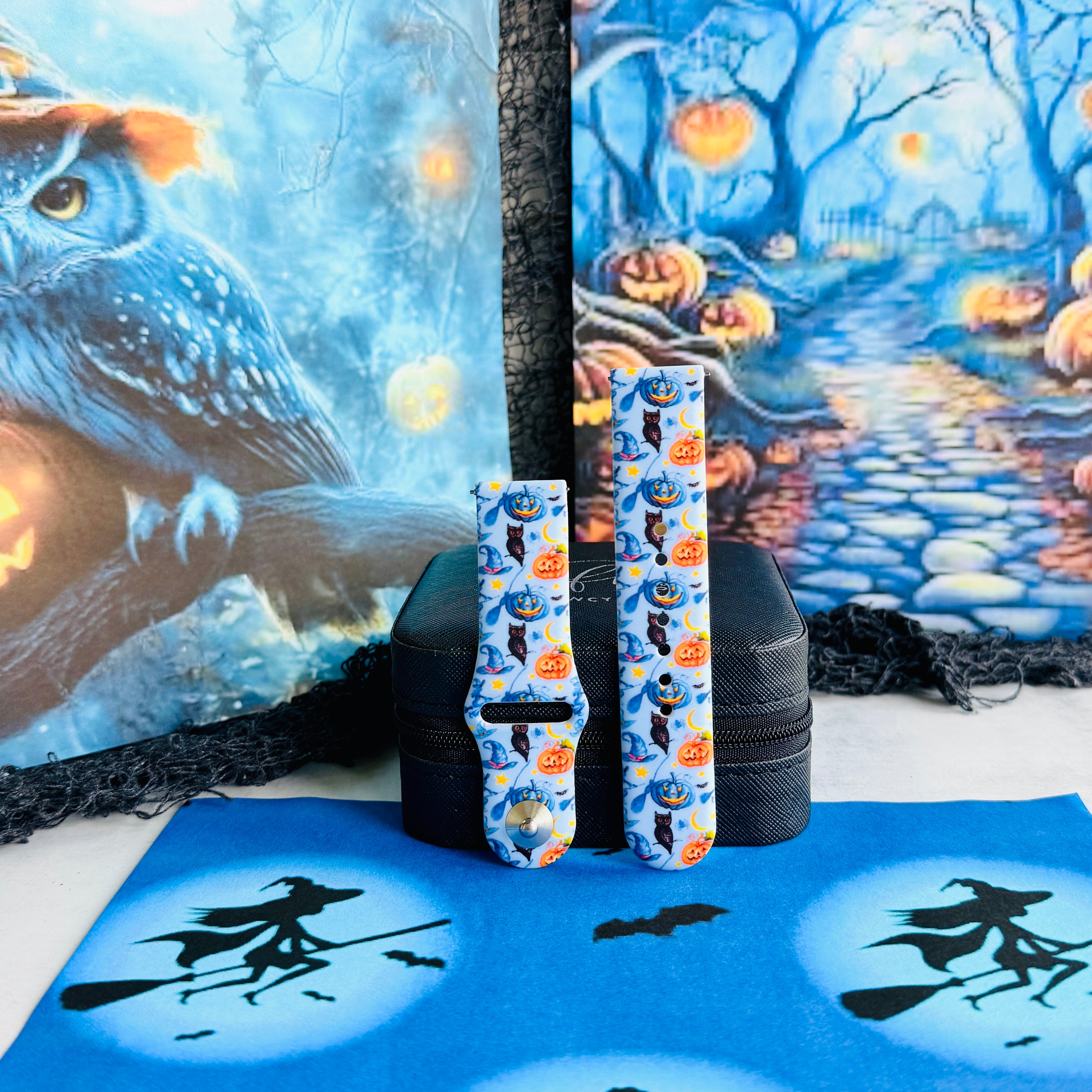 The Bewitching Hour Samsung Galaxy Watch band displayed beside a painted owl backdrop, light blue silicone with witch hats and jack-o-lanterns.
