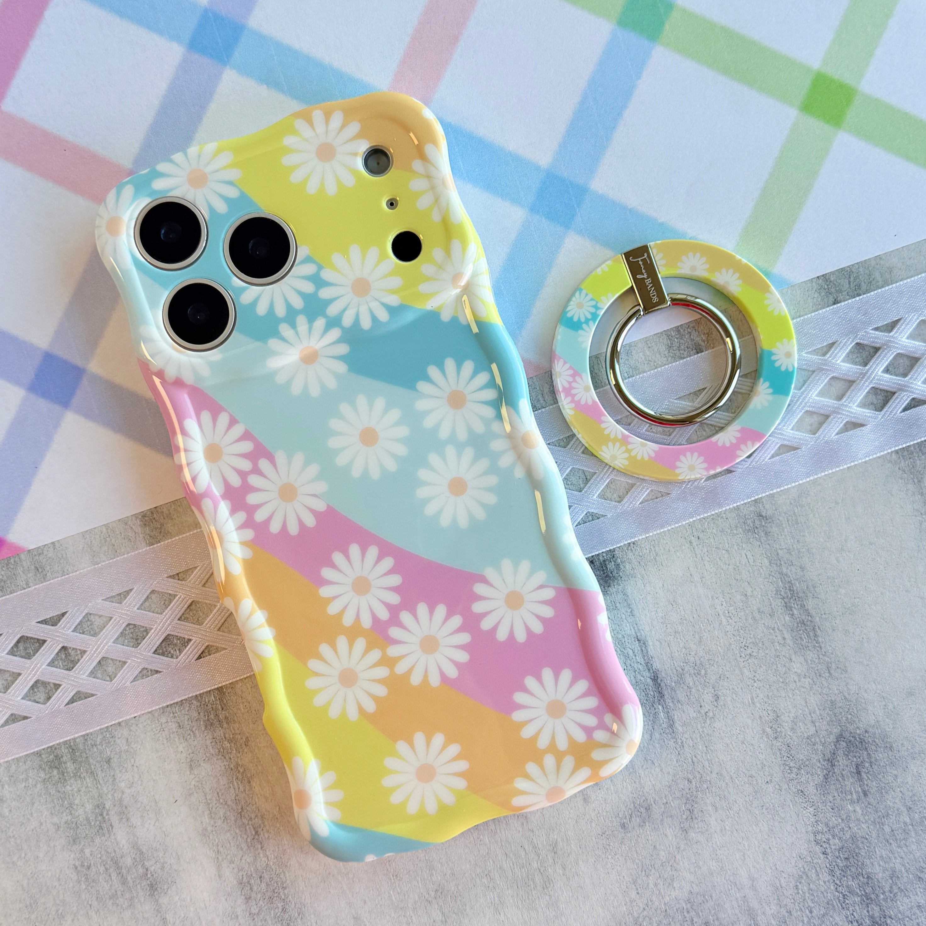 Daisy Dream MagSafe grip ring with pastel rainbow waves and white daisies on phone