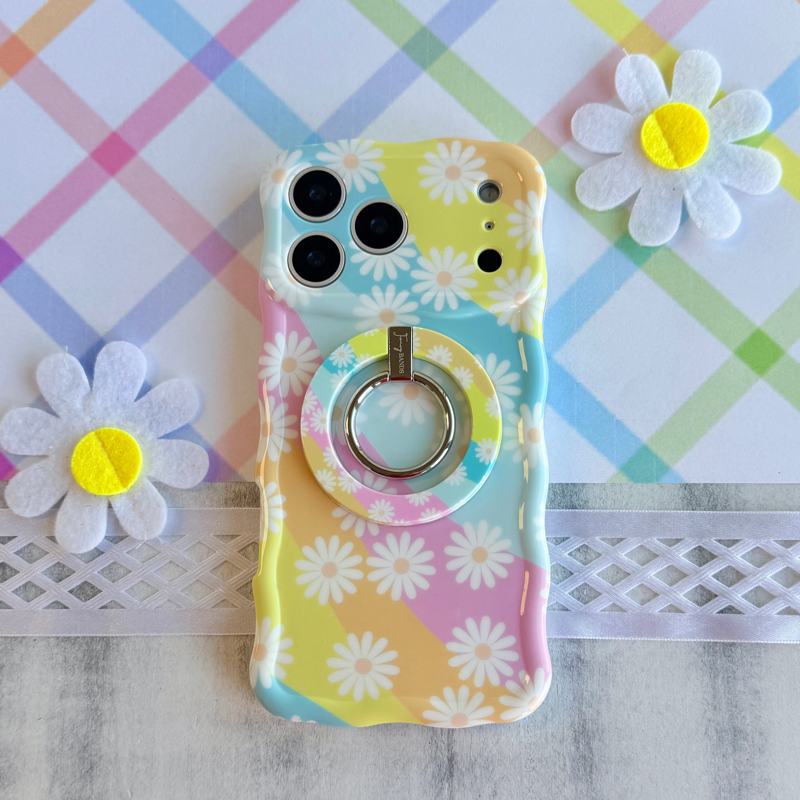 Daisy Dream MagSafe grip ring with pastel rainbow waves and white daisies on phone