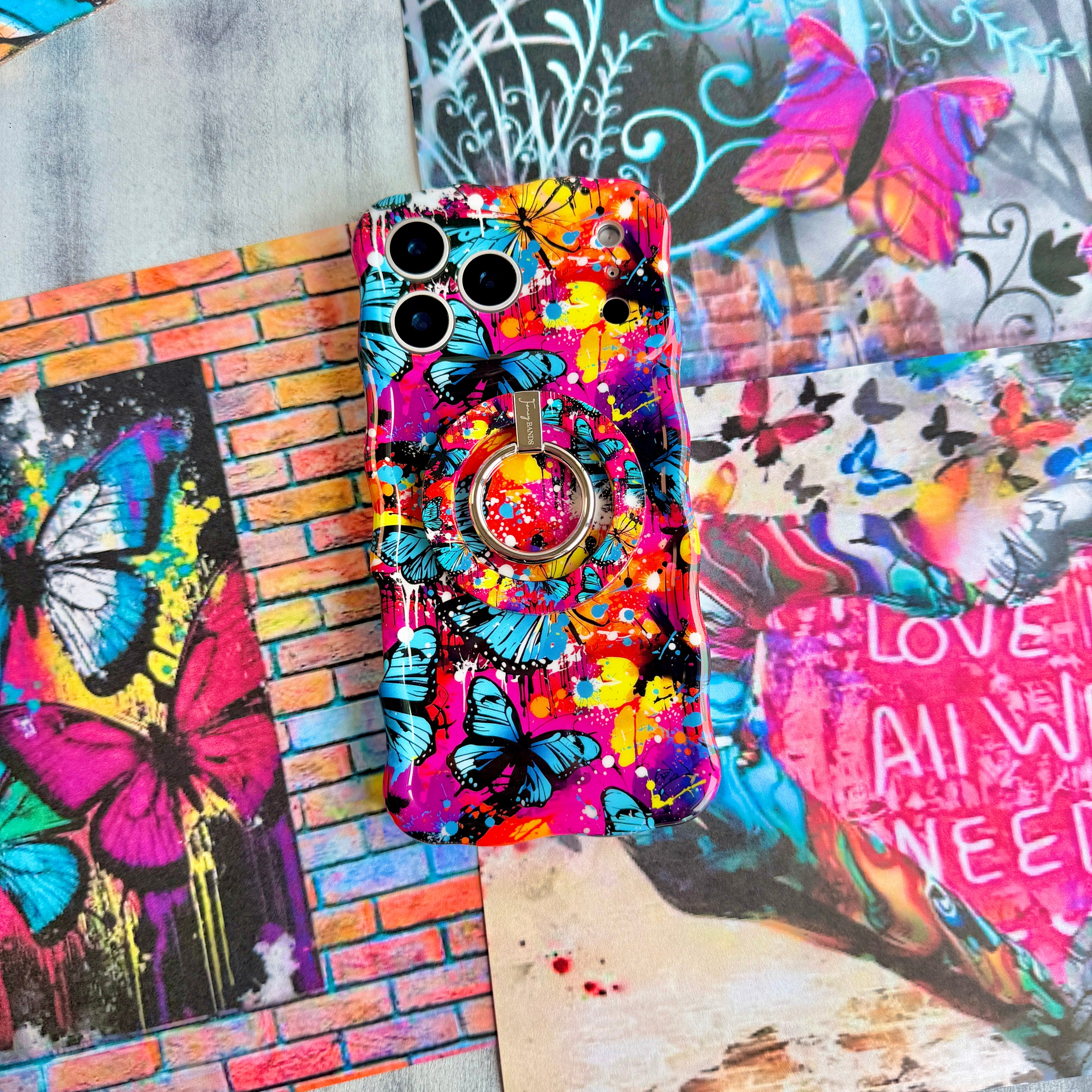 Rebel Wings graffiti butterfly MagSafe phone grip ring with electric blue butterflies, pink and orange paint splatters, and grunge street art design compatible with iPhone and Samsung