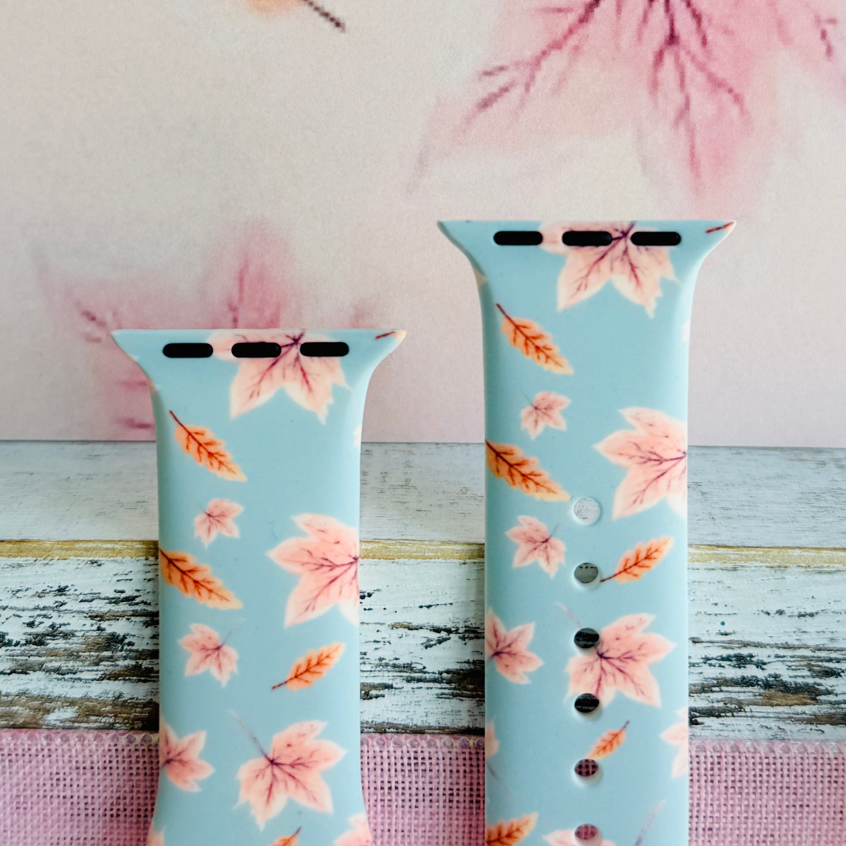 Both sizes of the Autumn Breeze Apple Watch band side by side, close view of the blush pink maple leaves on soft blue silicone.