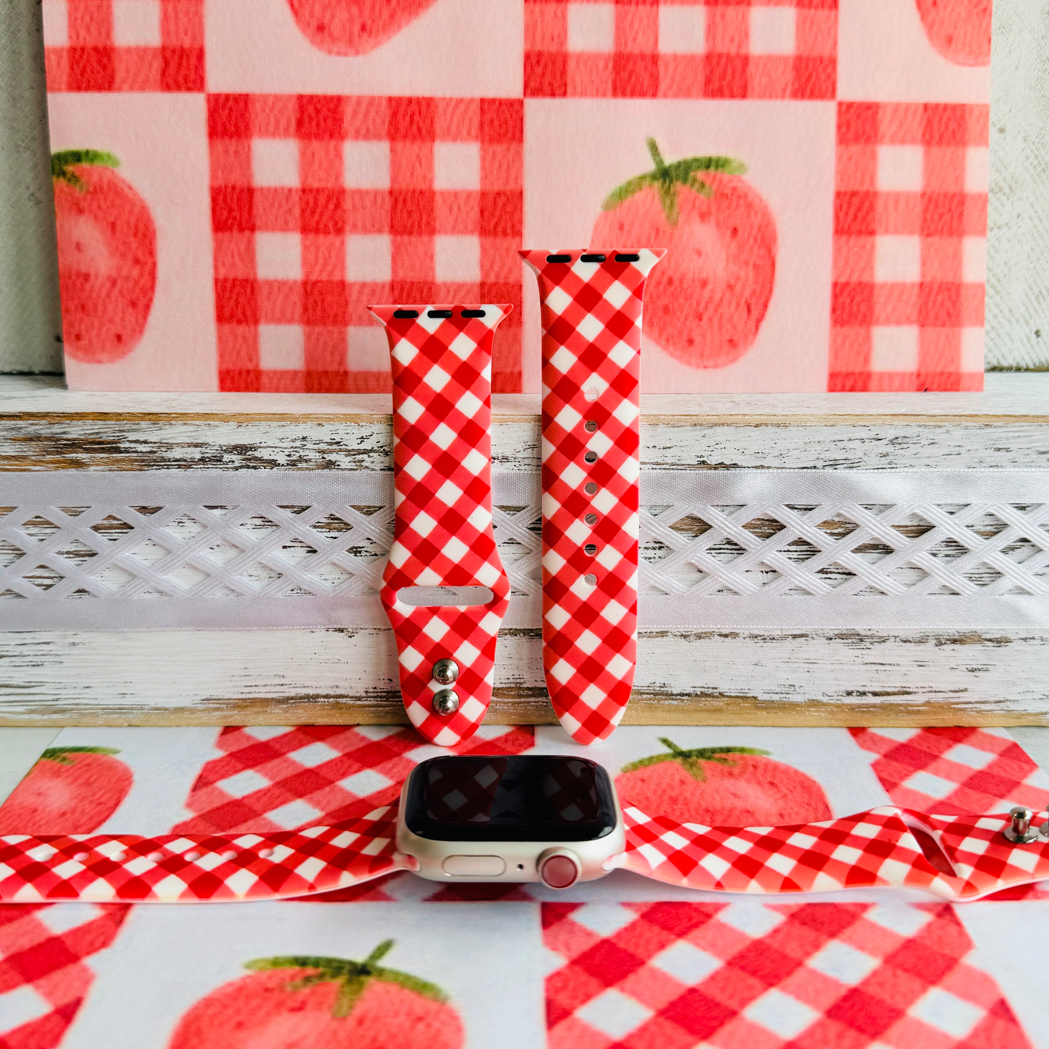 Red Barn Babe silicone Apple Watch band shown in both sizes with an Apple Watch at the base, red and white gingham cut on the bias.
