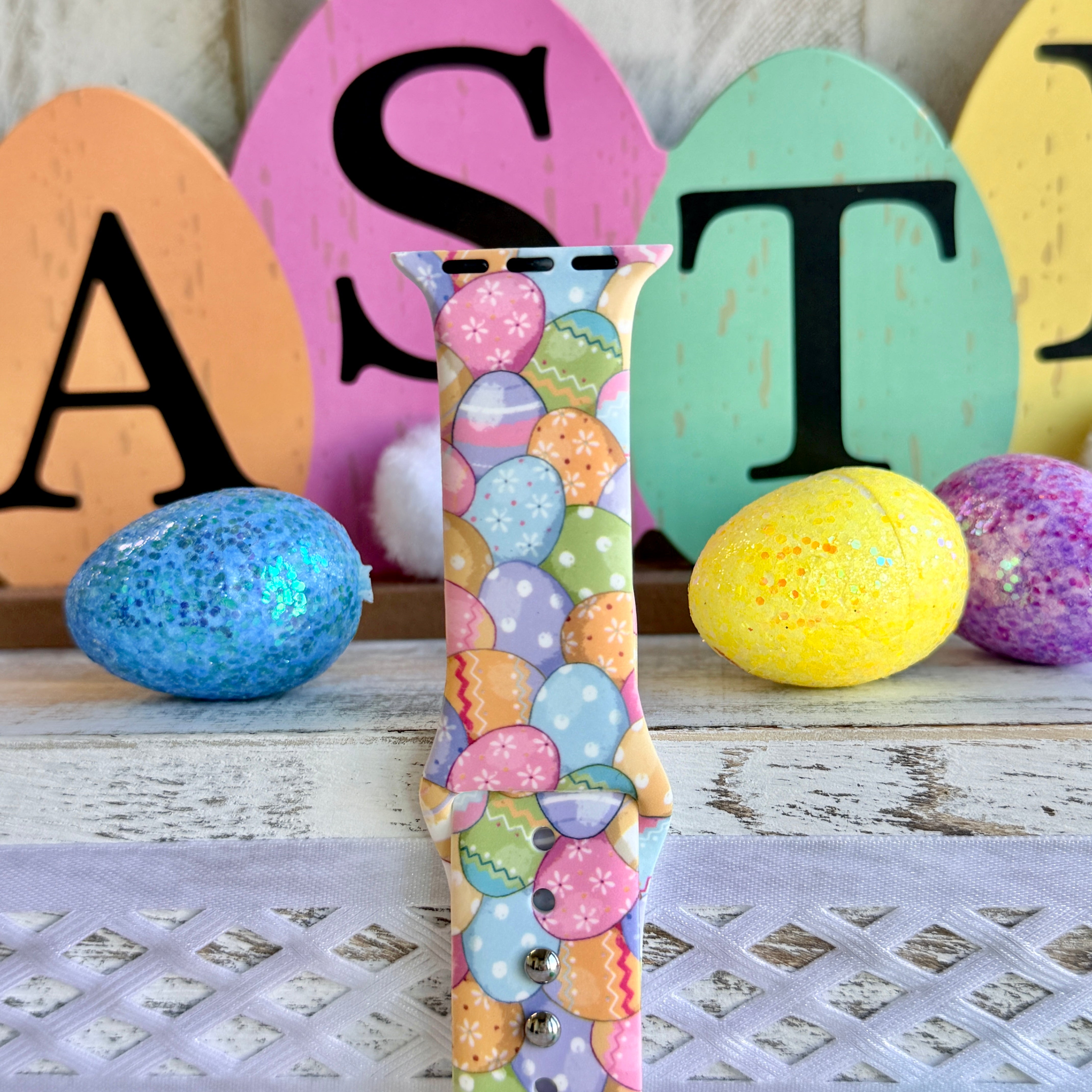 Egg-stra Cute Apple Watch band with colorful pastel Easter eggs displayed with glittery eggs and Easter decorations