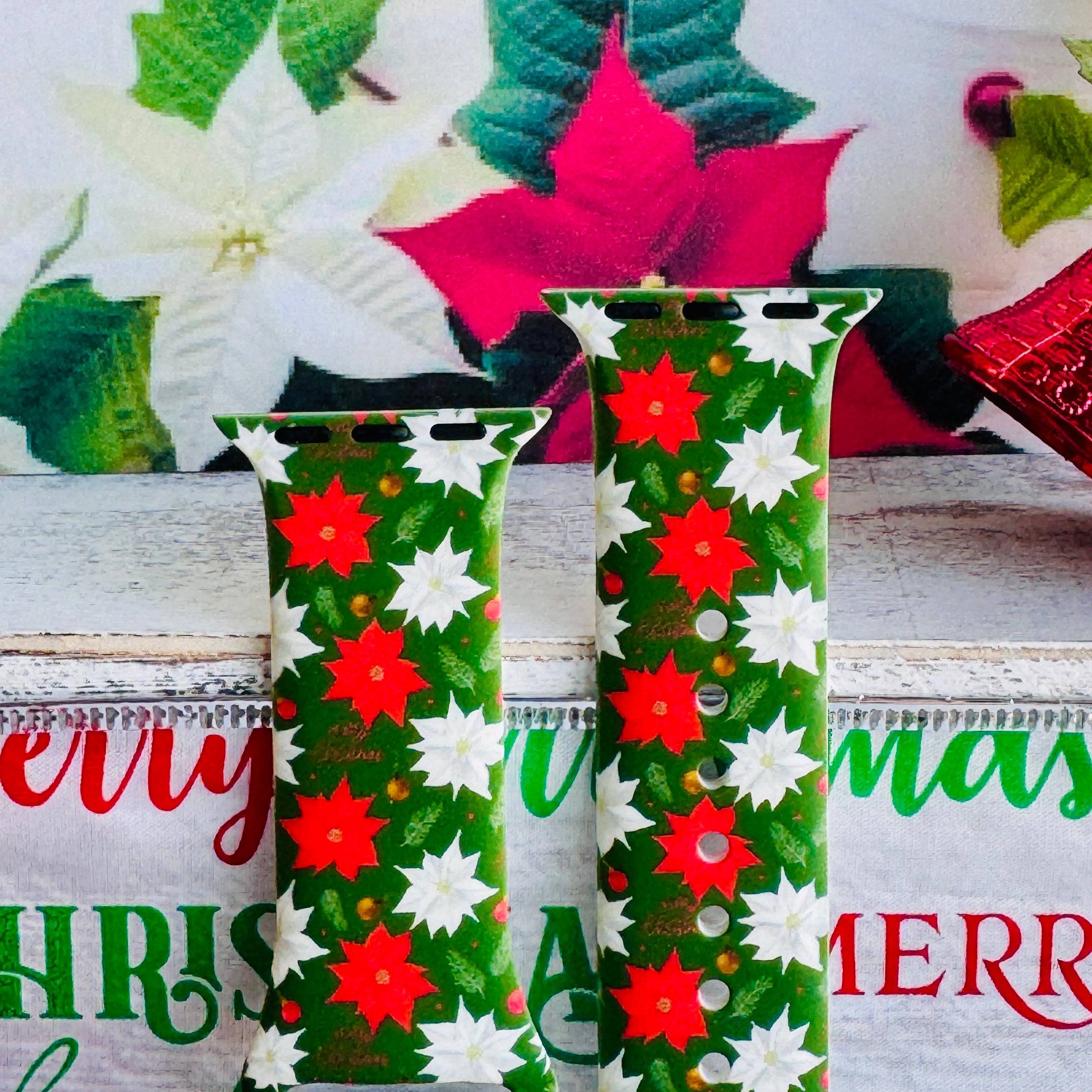 Close-up of Poinsettia Pines print showing vibrant red flowers, white blooms, and lush green pine on Apple Watch silicone band