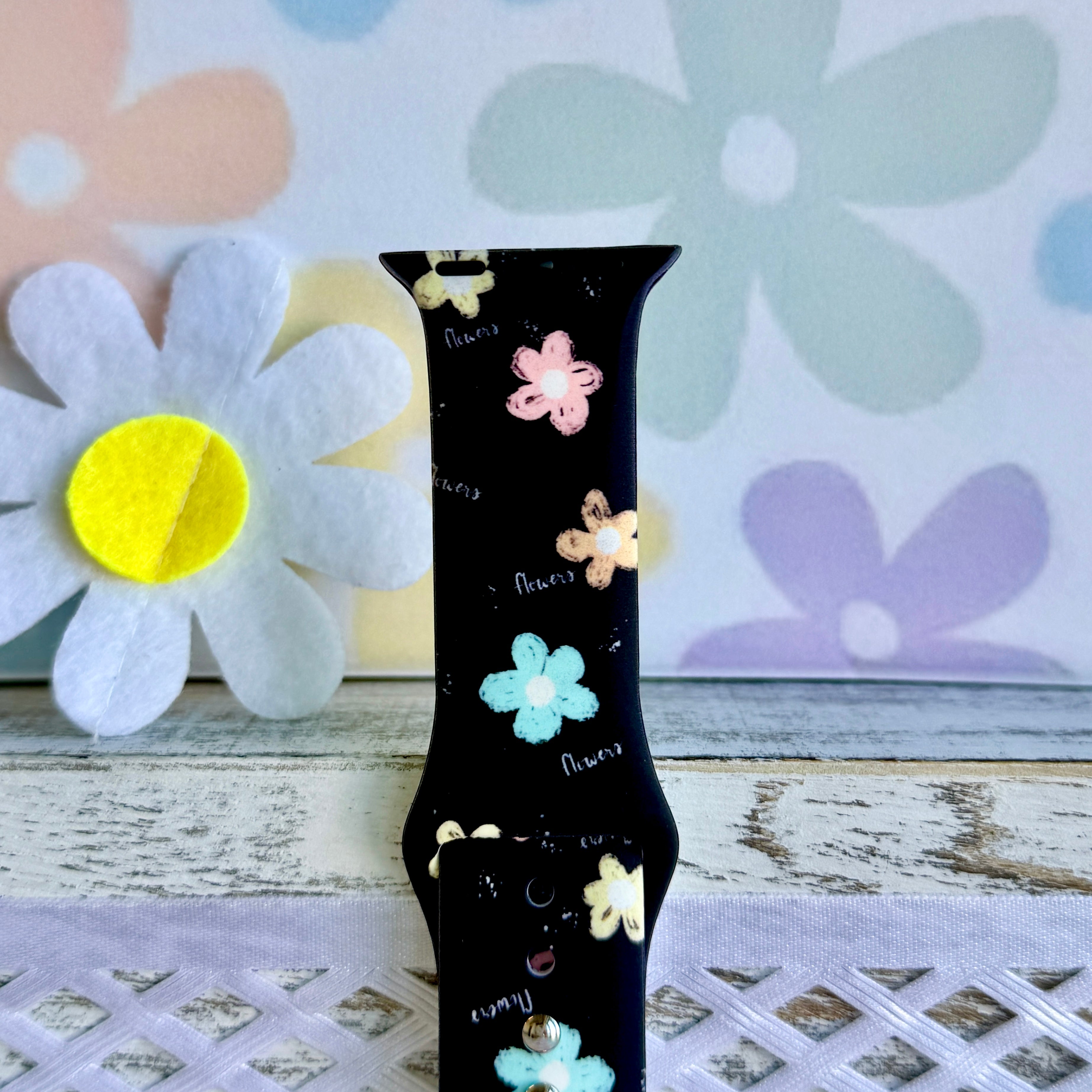 Flower Pop Apple Watch band with pastel flowers in pink, yellow, turquoise, and peach on black background with daisy decorations