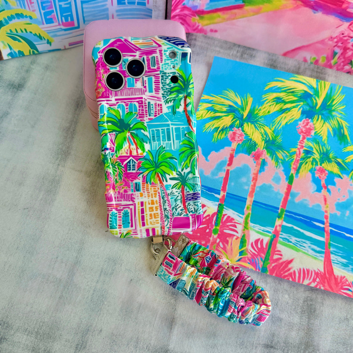La Palma Villa scrunchie phone wrist strap laid out with the matching tropical resort Wavy Luxe iPhone case