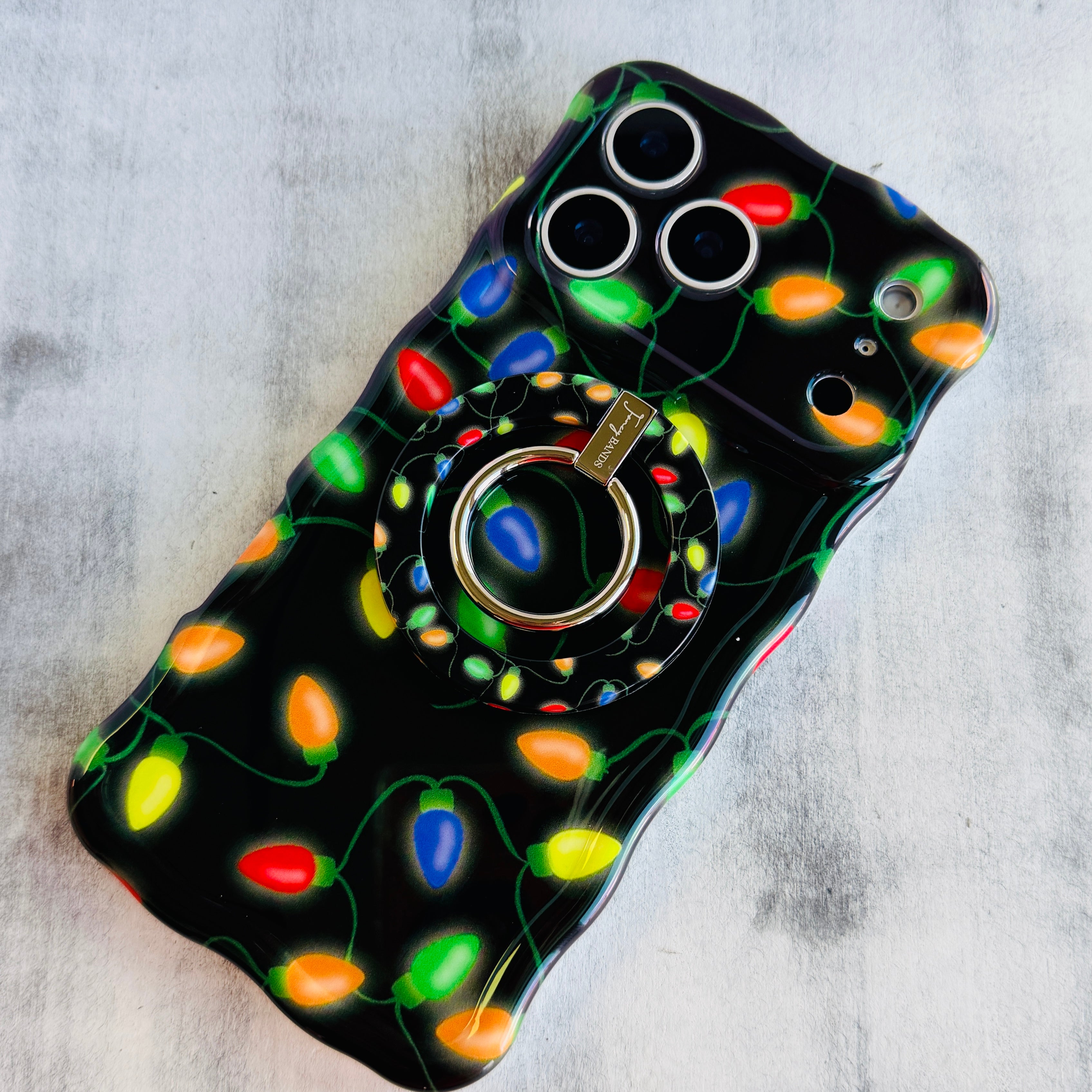 Phone case with colorful Christmas light design on a gray surface