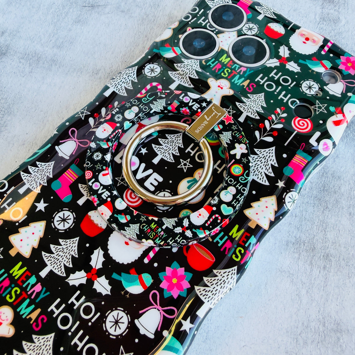 Jolly Wrist-mas Hold It Fancy MagSafe grip ring snapped onto the matching black Christmas iPhone case