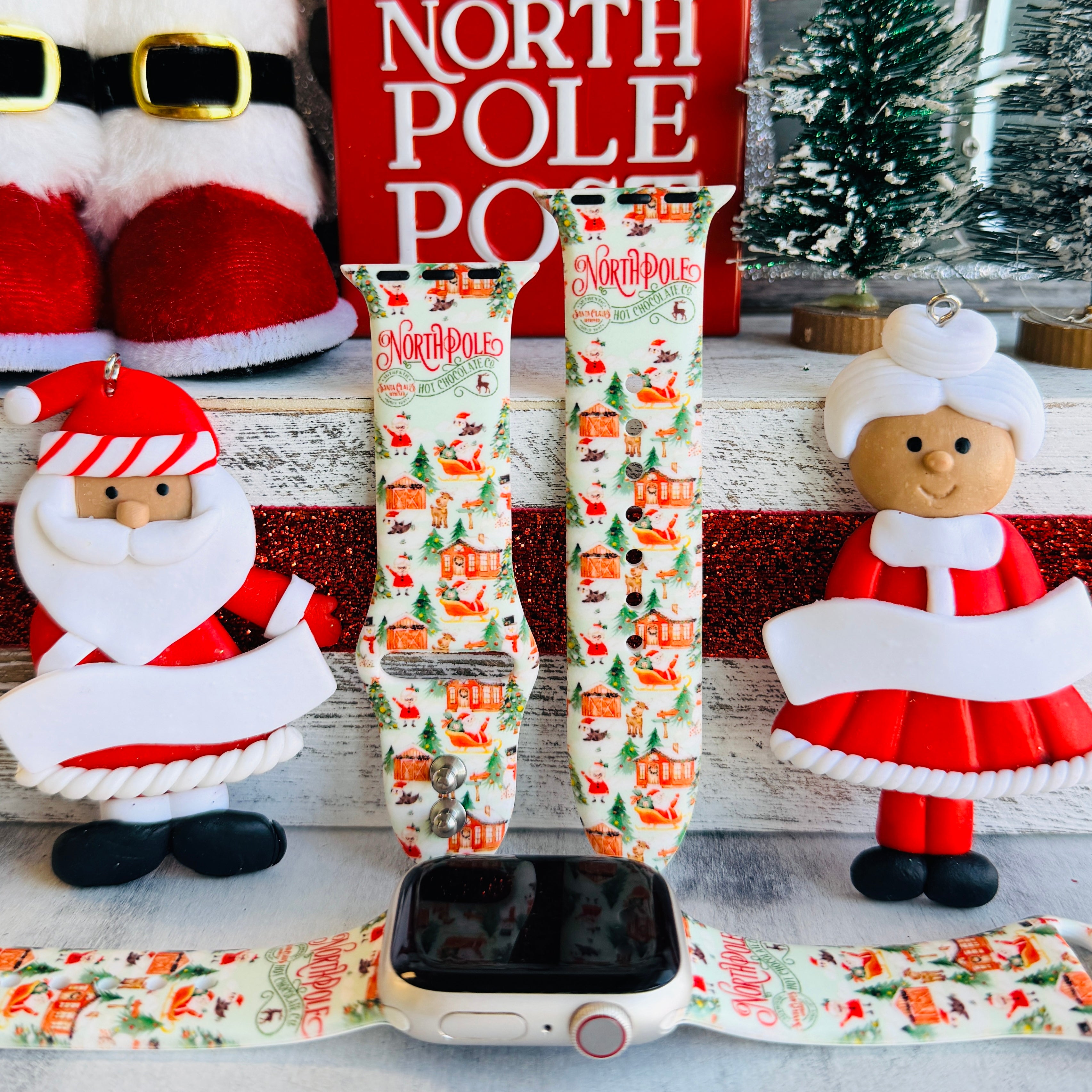 North Pole Apple Watch band with Santa's workshop, Christmas trees, and reindeer on cream background with North Pole sign