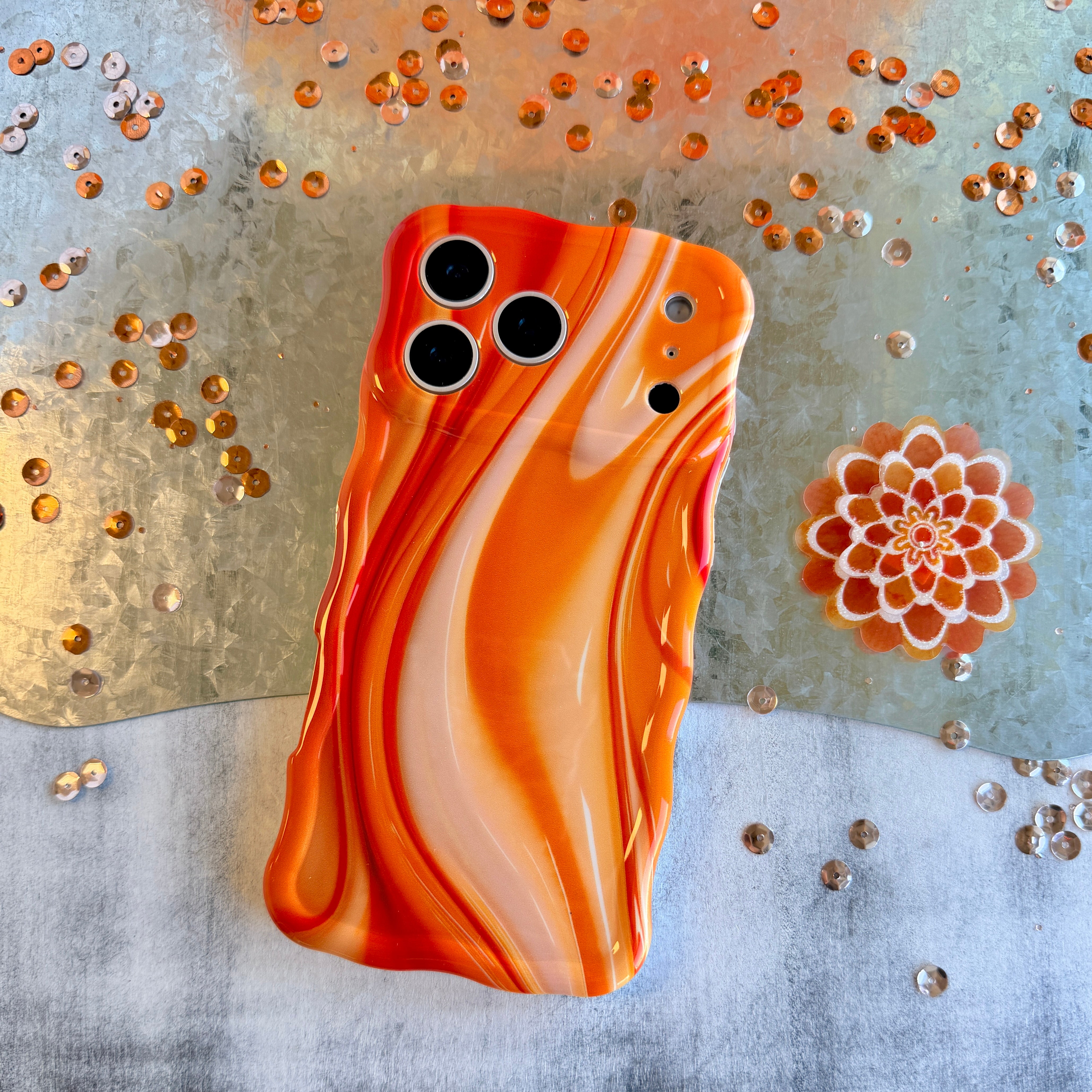 Orange and white marbled phone case on a decorative background with gold and silver elements.