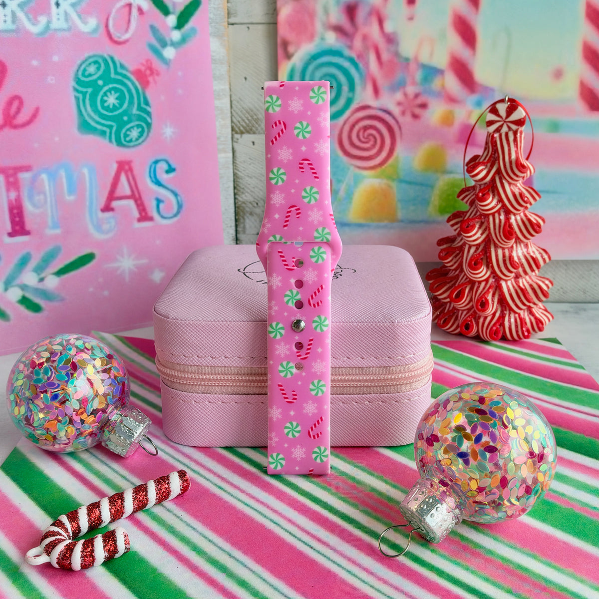 Peppermint Cutie Samsung watch band strap standing beside a red and white peppermint tree and glitter ornaments
