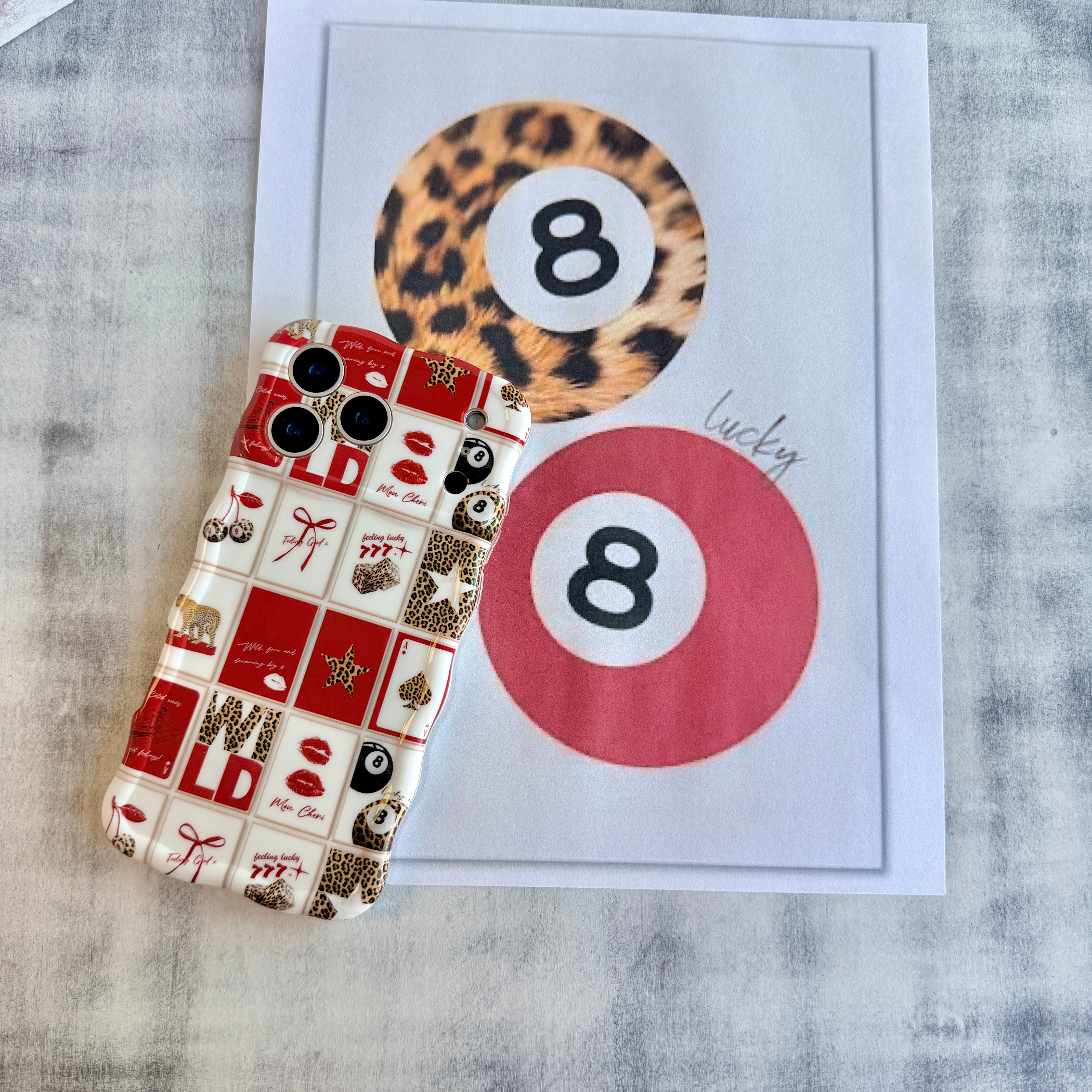 Trendy red and white wavy iPhone case featuring a collage of leopard print cherries, 8-balls, red lips, and lucky 777 dice with a high-gloss finish.