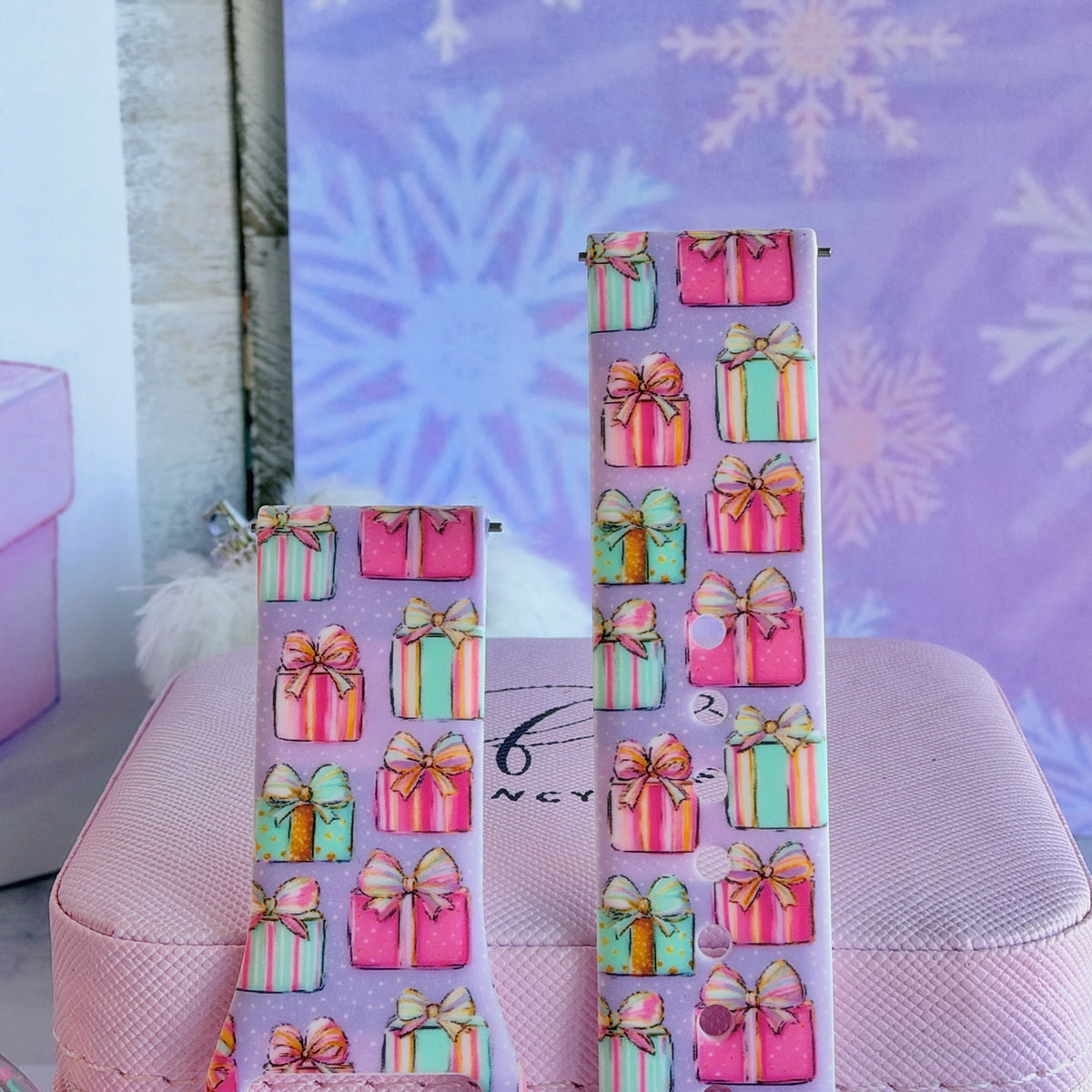 Close-up of both No Peeking, Darling Samsung Galaxy Watch band straps with pastel gift boxes and gold-edged bows