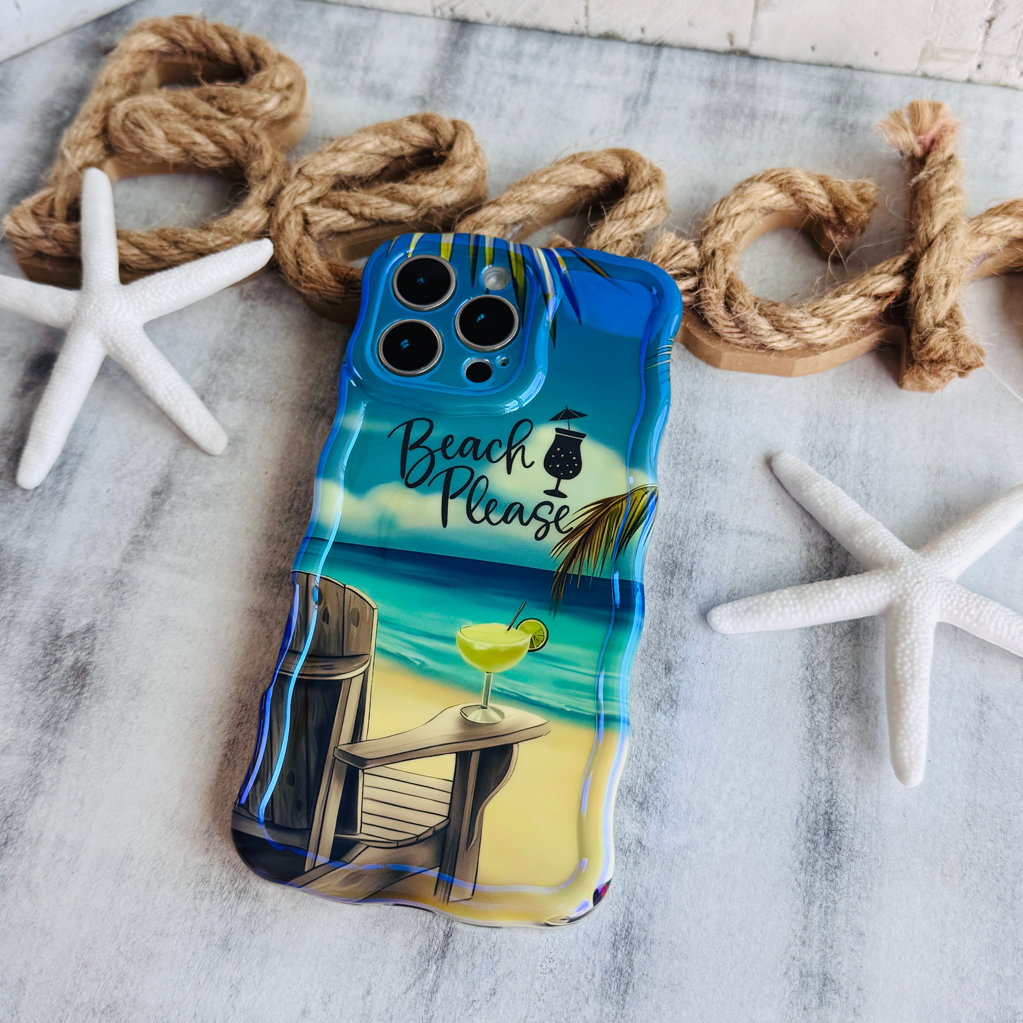 Phone case with beach-themed design on a marble surface with rope and starfish.