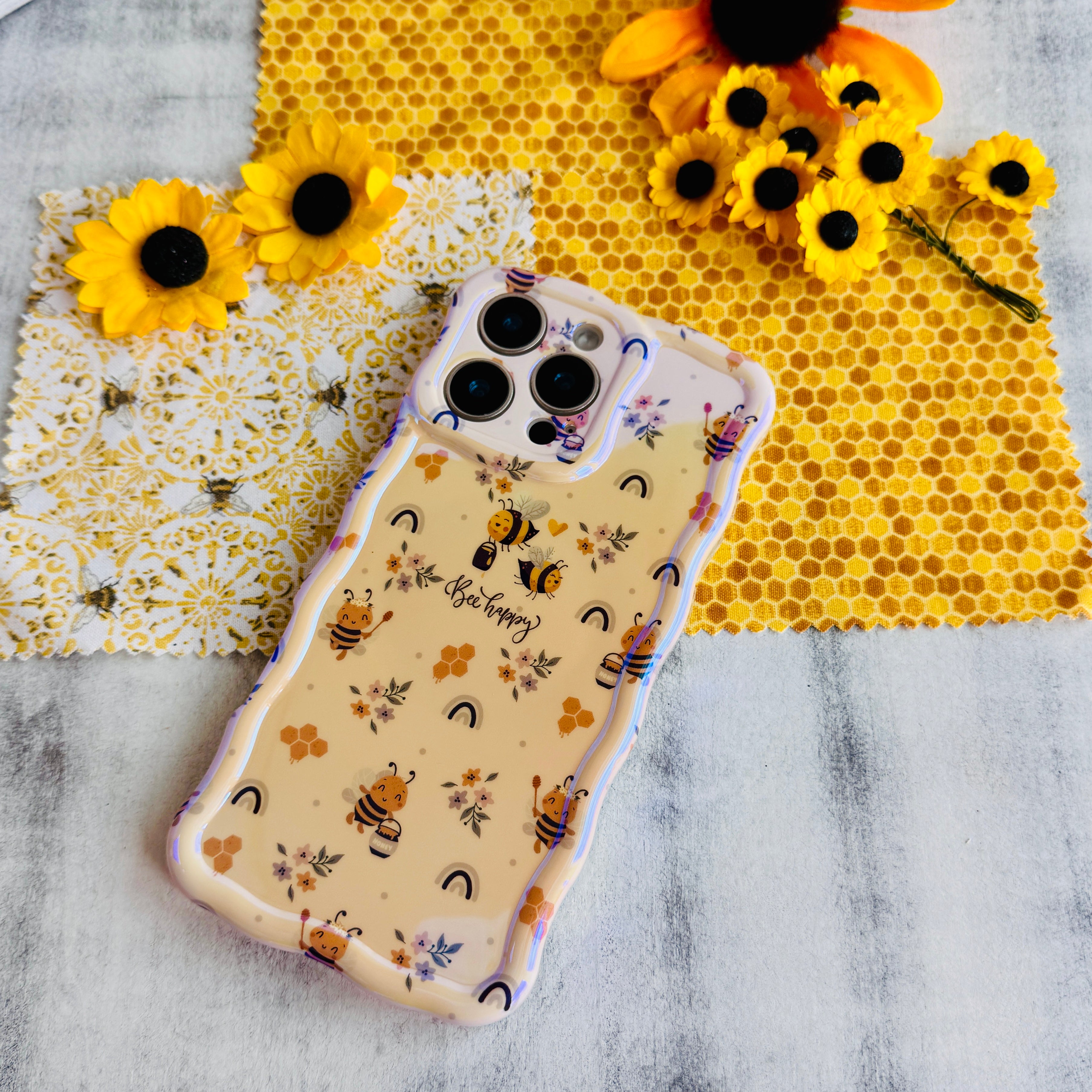 Phone case with bee and sunflower design on a honeycomb background.