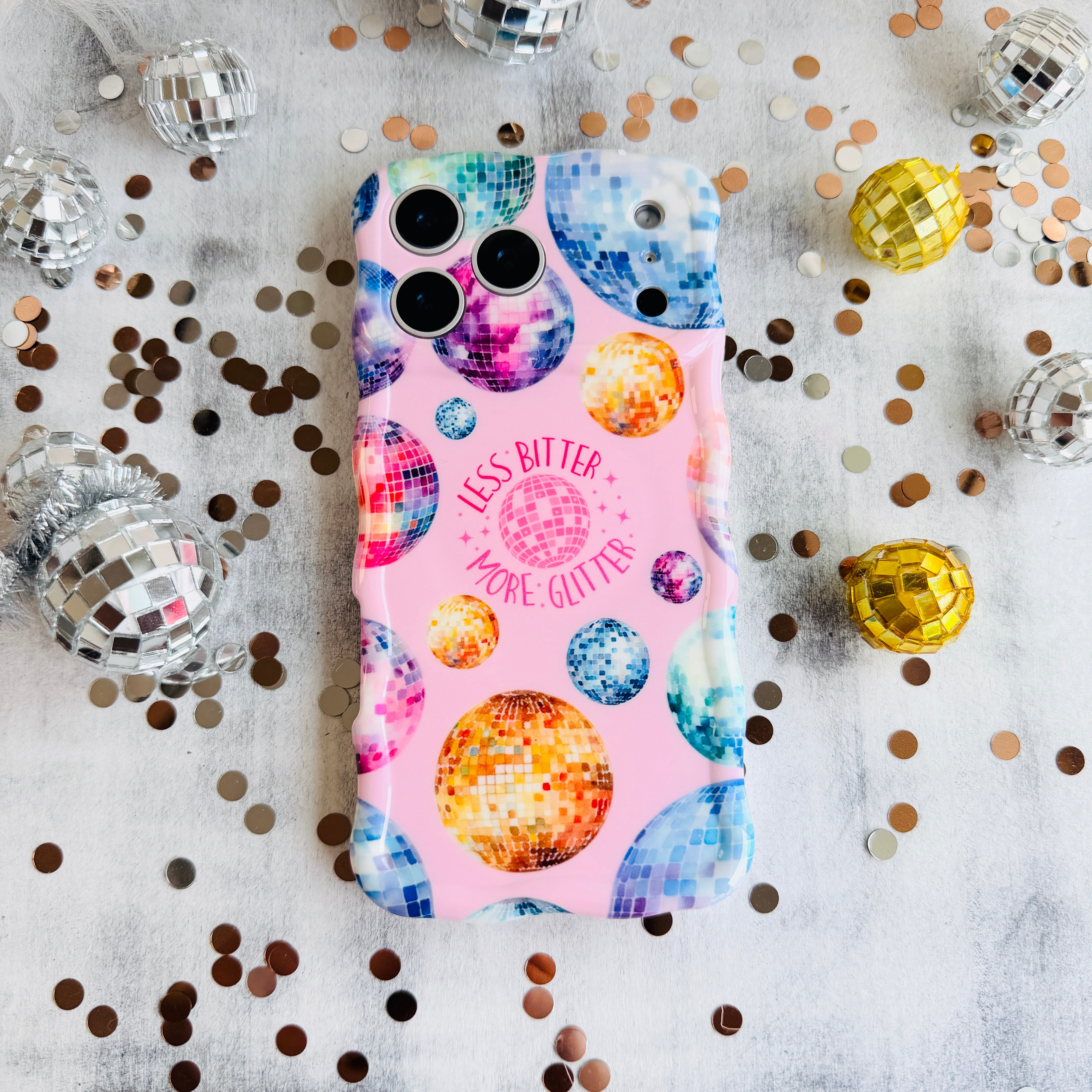 Pink wavy iPhone case featuring colorful retro disco balls and the quote Less Bitter More Glitter, held in hand with MagSafe compatibility.