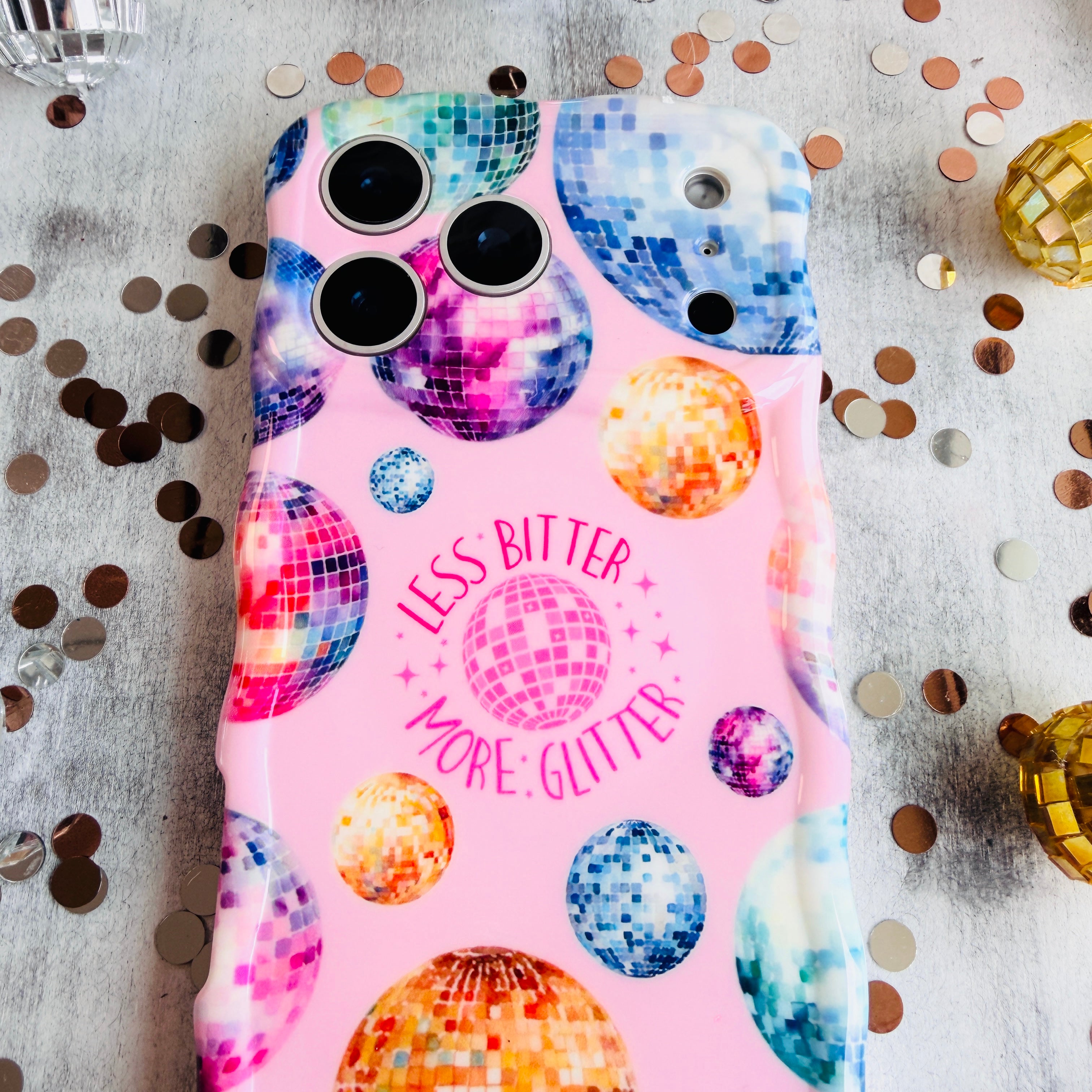 Pink wavy iPhone case featuring colorful retro disco balls and the quote Less Bitter More Glitter, held in hand with MagSafe compatibility.