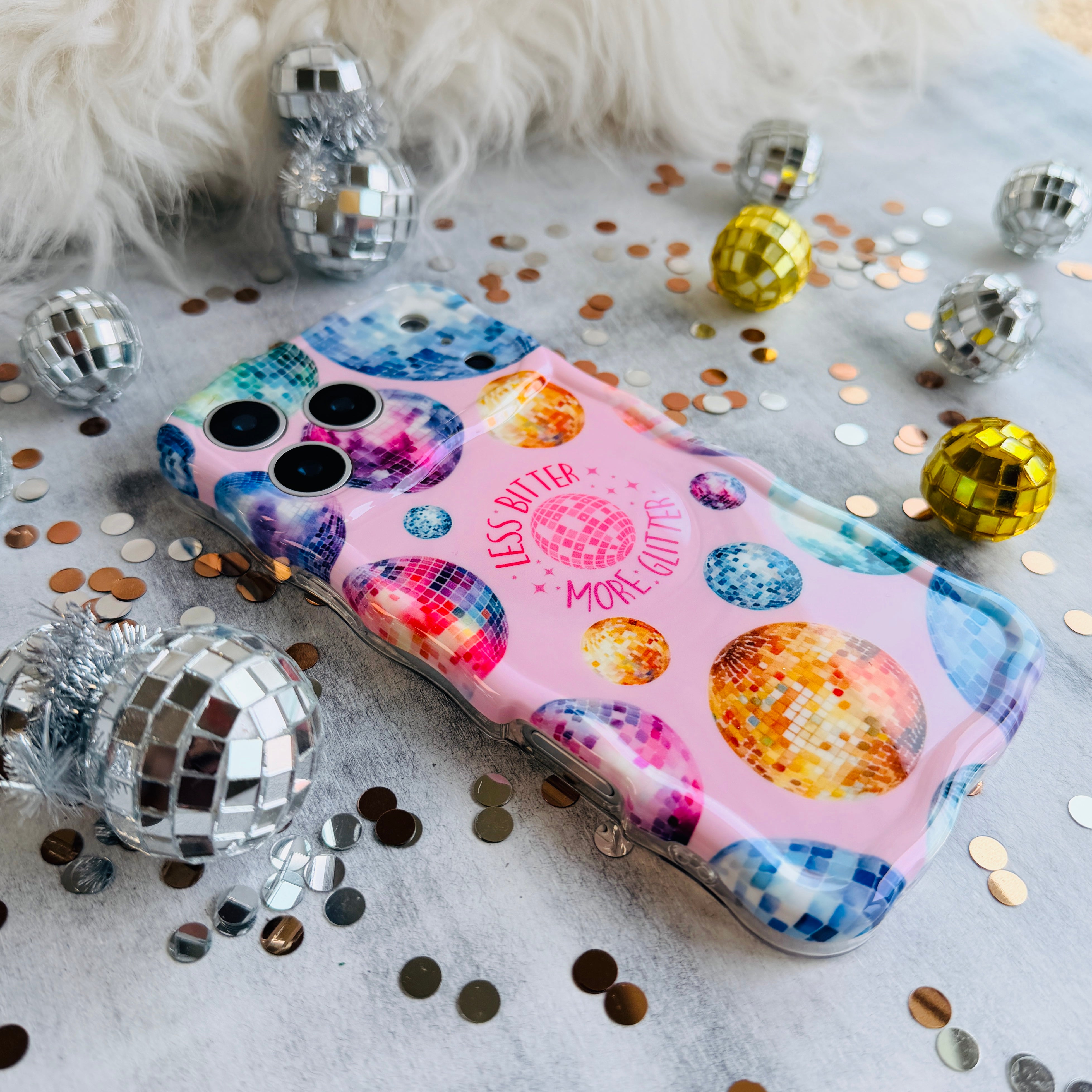 Pink wavy iPhone case featuring colorful retro disco balls and the quote Less Bitter More Glitter, held in hand with MagSafe compatibility.