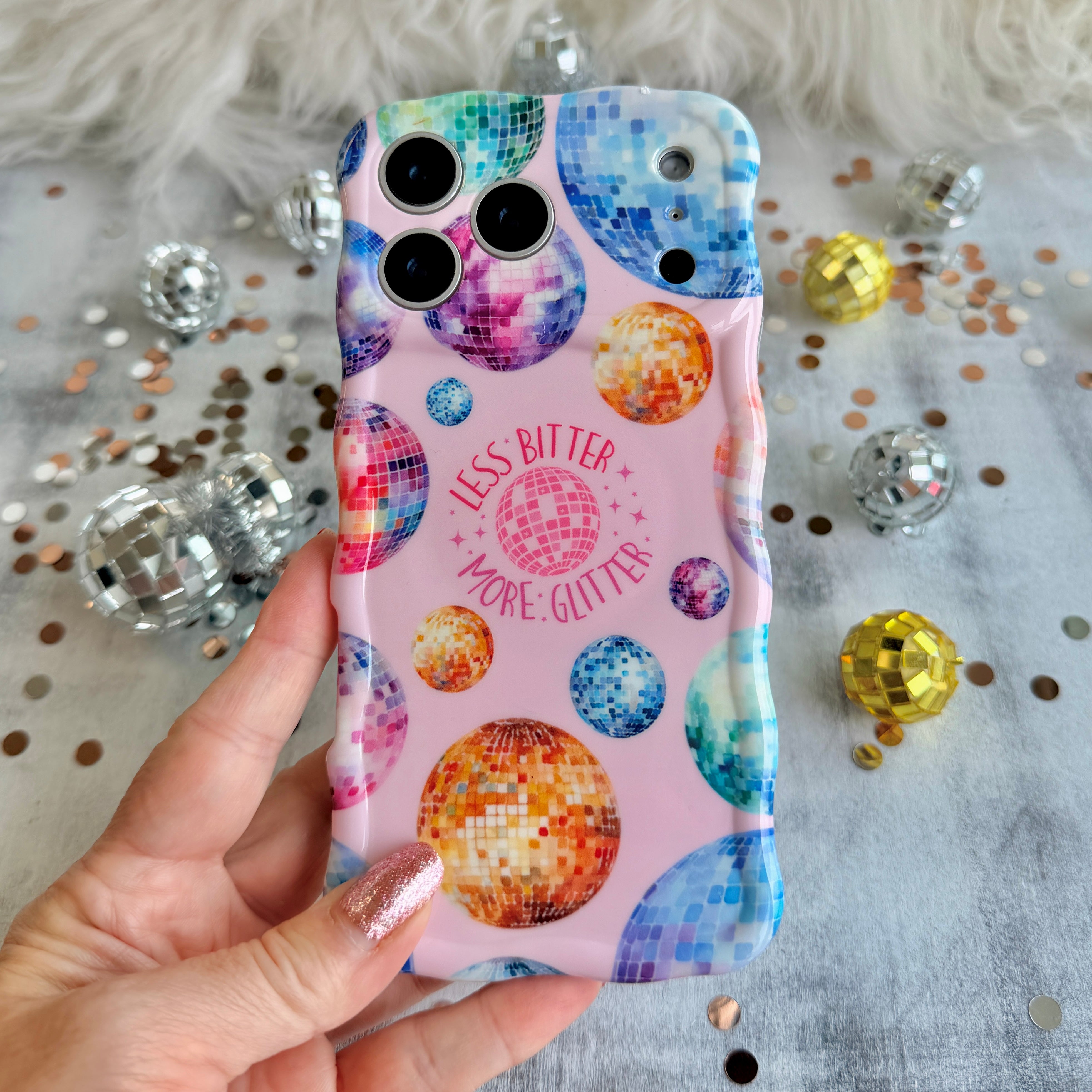 Pink wavy iPhone case featuring colorful retro disco balls and the quote Less Bitter More Glitter, held in hand with MagSafe compatibility.