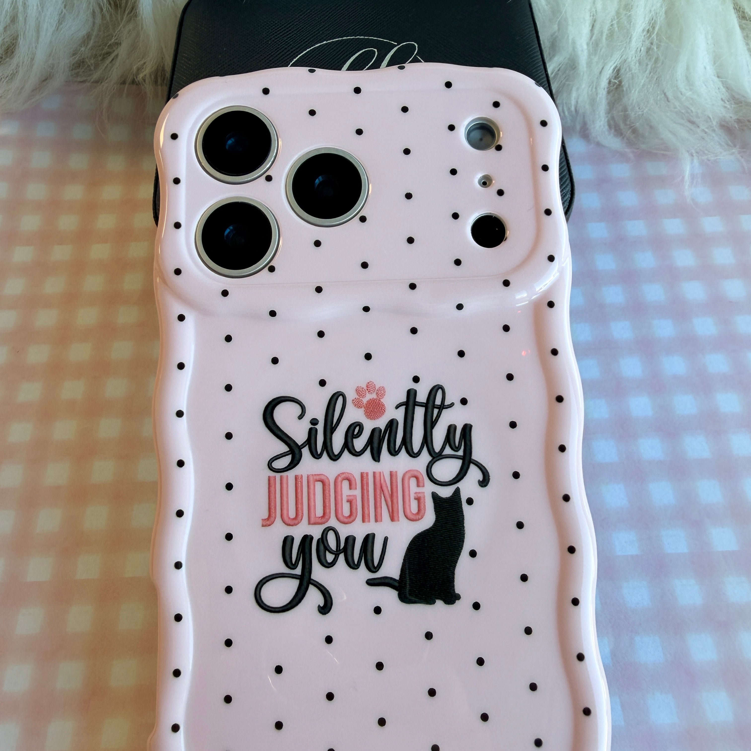 Light pink wavy iPhone case with black polka dots featuring a black cat silhouette and the text Silently Judging You.