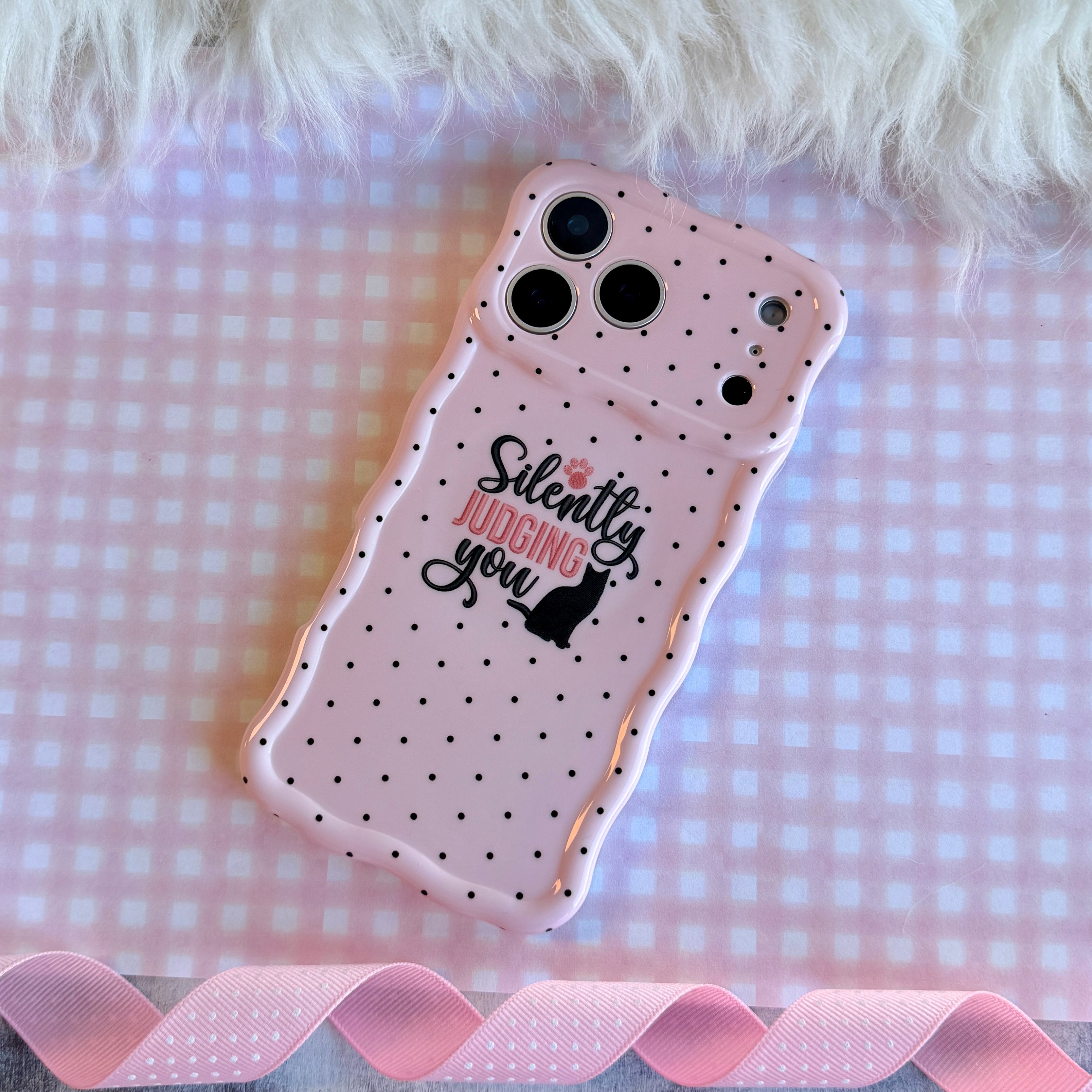 Light pink wavy iPhone case with black polka dots featuring a black cat silhouette and the text Silently Judging You.