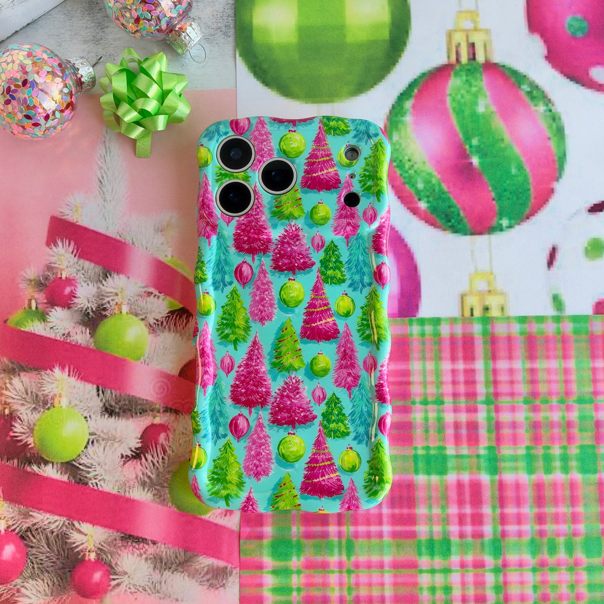 Merry & Bright, Totally! iPhone case lying flat on pink and green plaid beside a lime gift bow, pink ribbon and confetti-filled ornaments