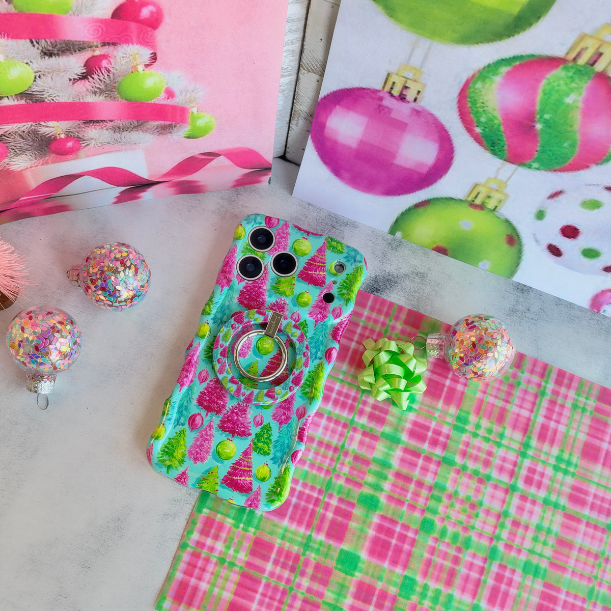 Merry & Bright, Totally! iPhone case with the matching grip ring snapped on, on pink and green plaid with a lime gift bow and confetti ornaments