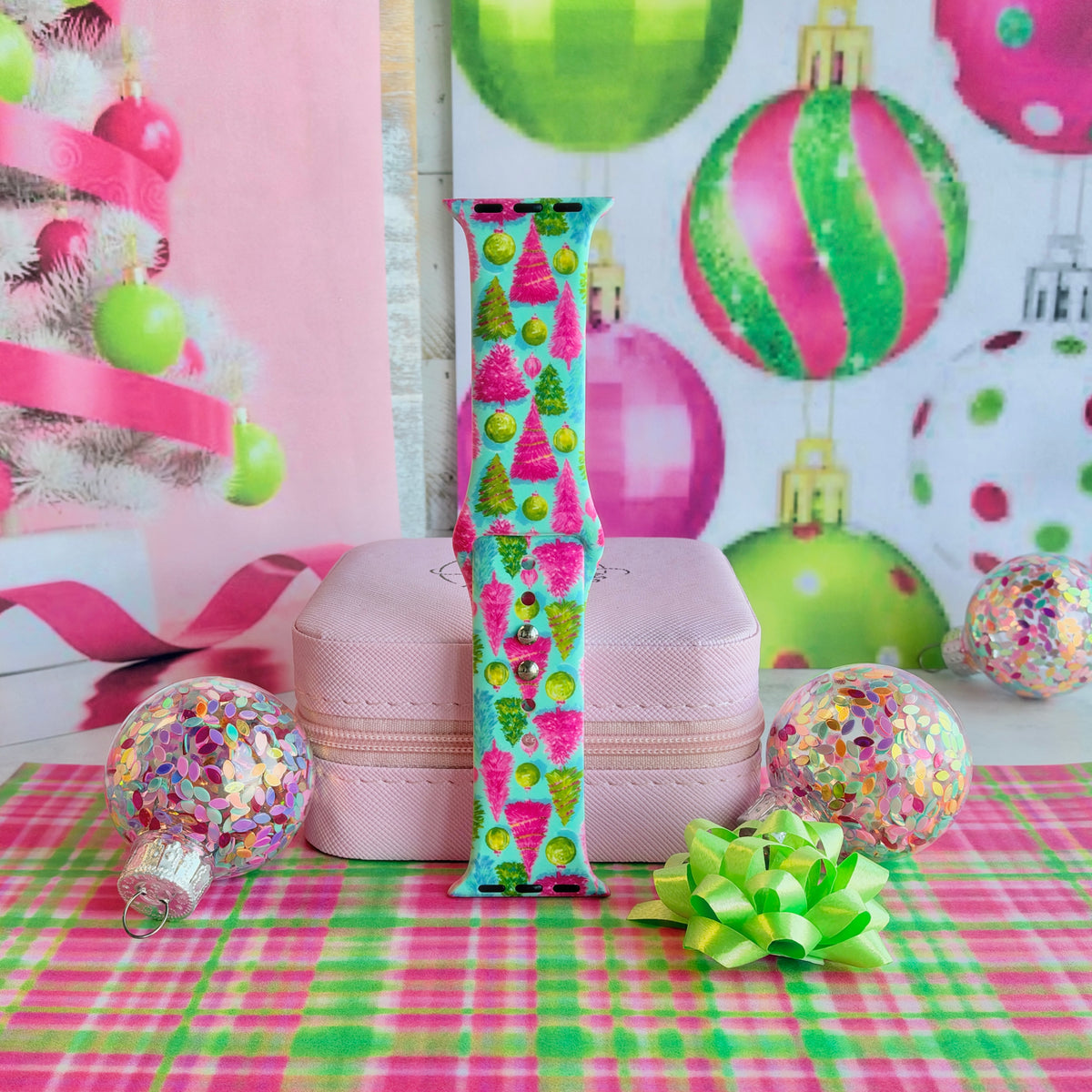 Single Merry & Bright, Totally! Apple Watch band strap standing on a pink jewelry box with big pink and green ornaments behind